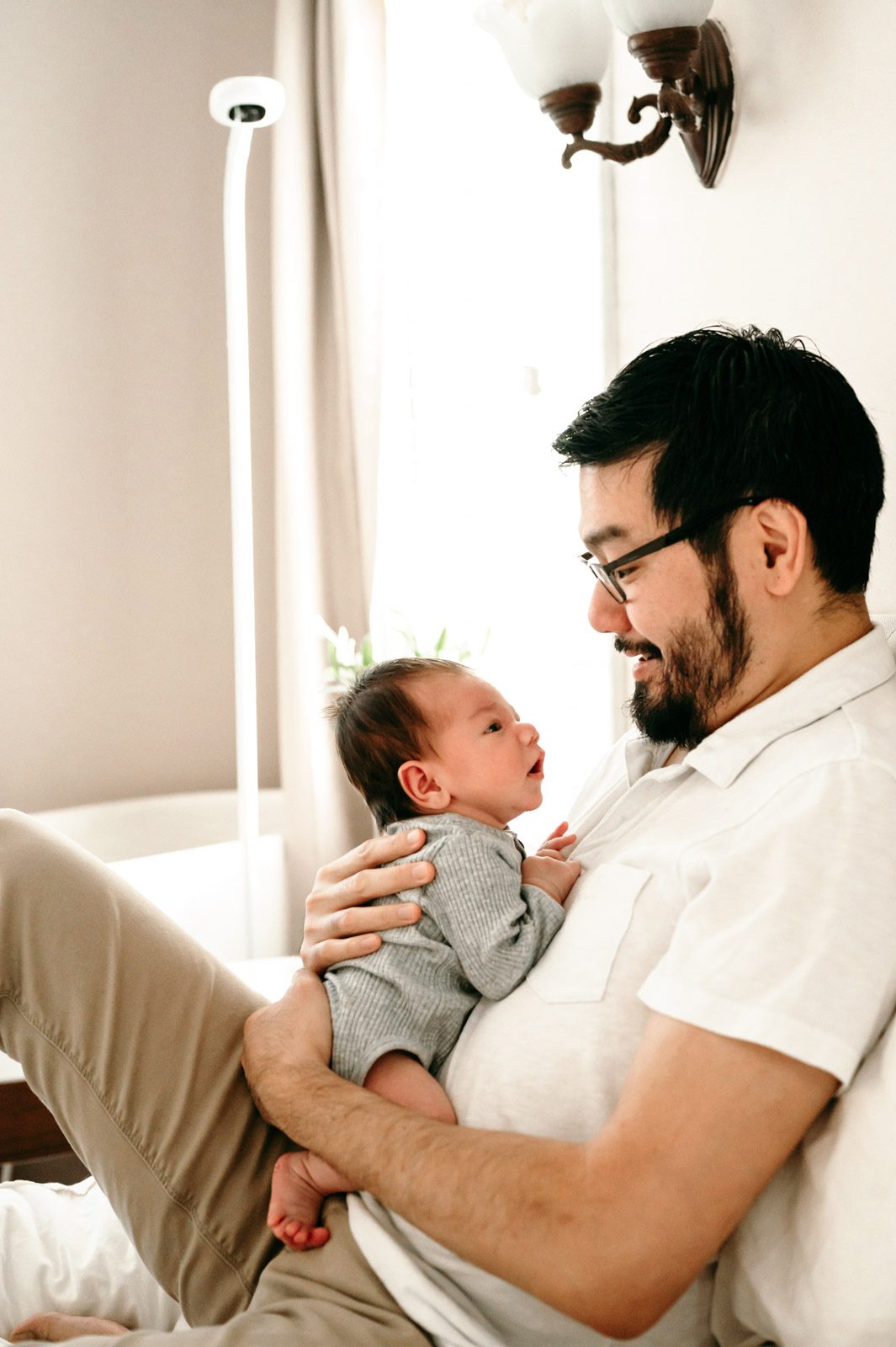 a new father snuggling his newborn son against his chest during an in home newborn session