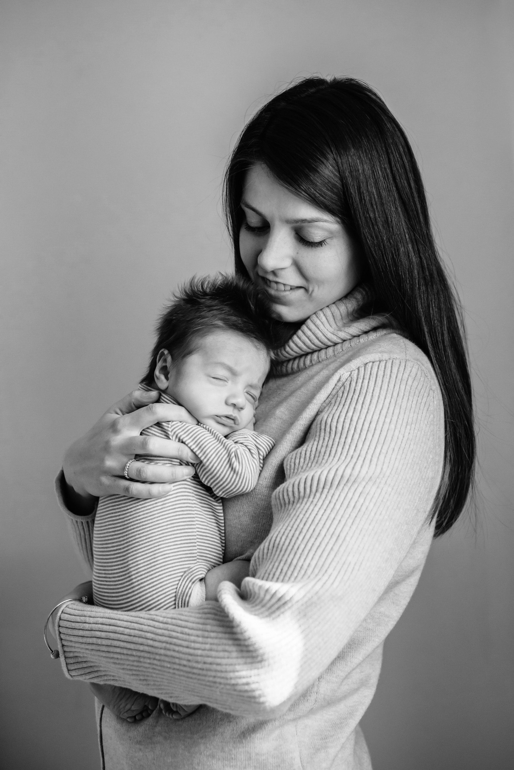 Newborn photo of a mom snuggling her baby boy against her chest during a natural newborn photoshoot