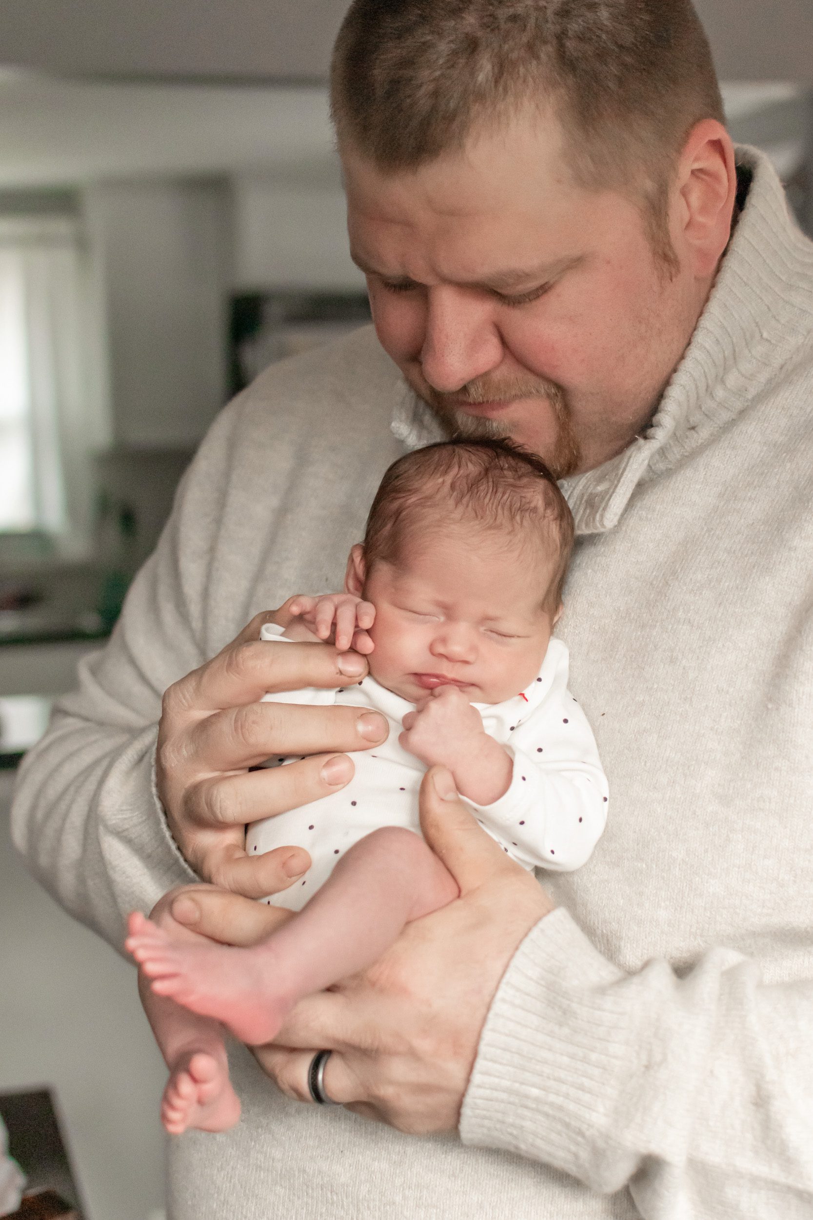 Newborn photo of dad holding his baby girl and looking down at her during an in home newborn photo session