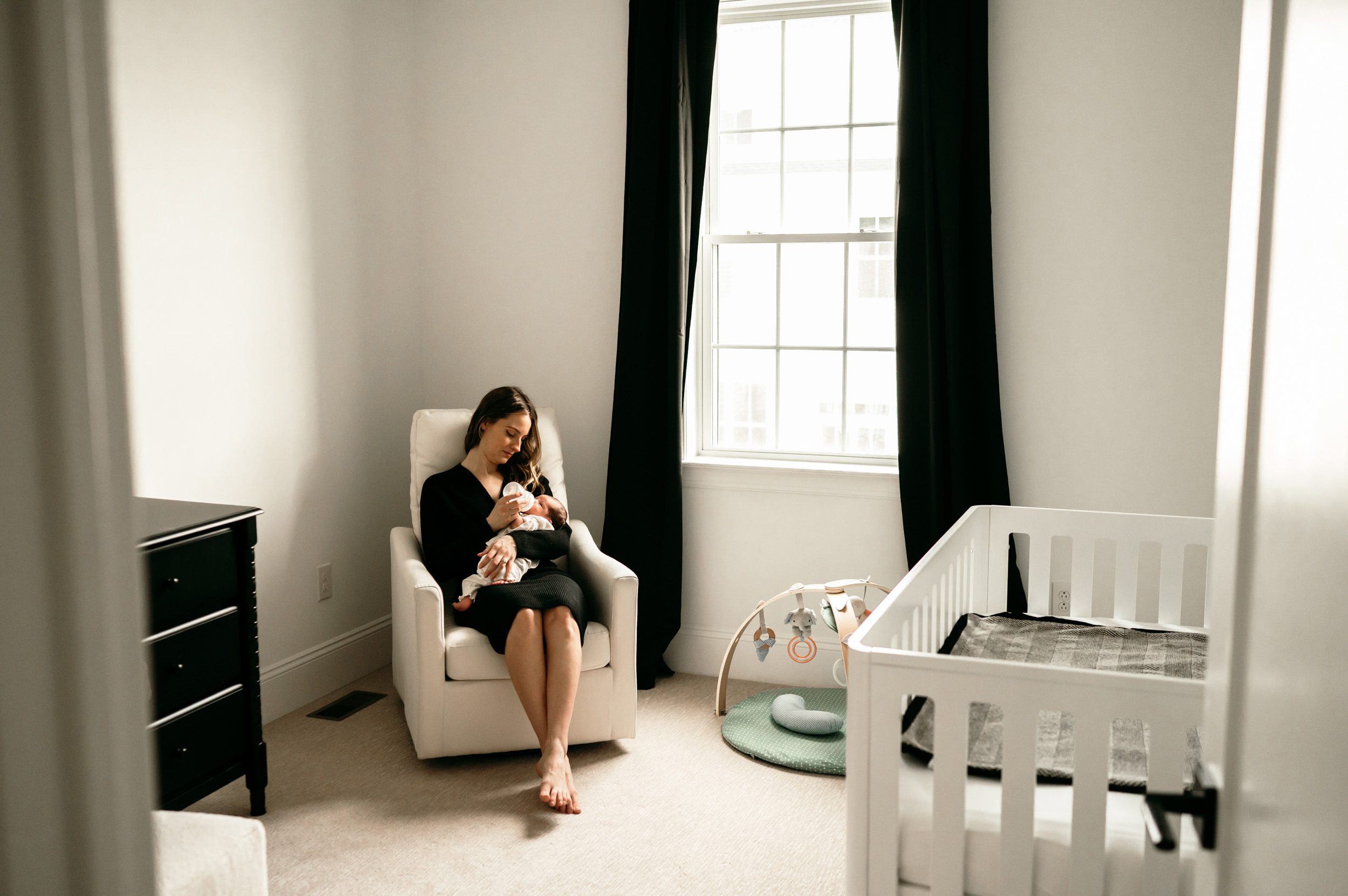 Newborn picture of a mom holding her baby girl in the rocking chair in her nursery during a natural newborn photo session
