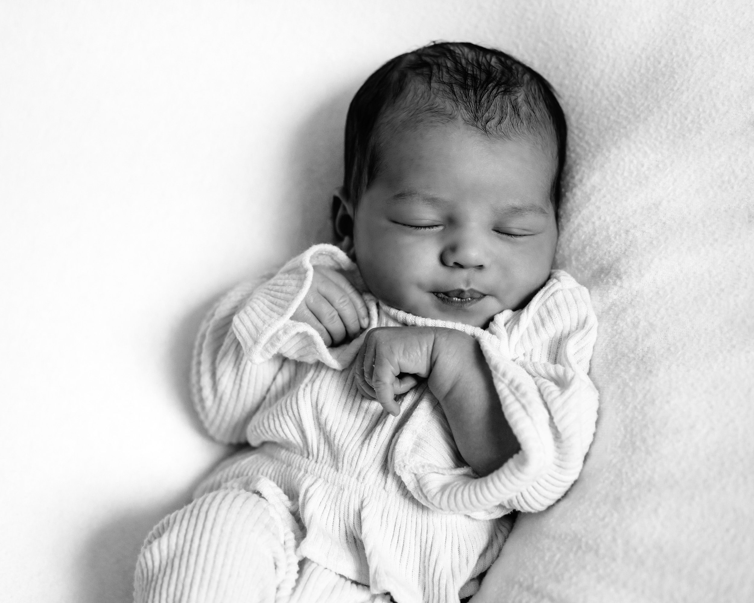 Black and white photo of a newborn girl sleeping on a white background during a phoenixville newborn session