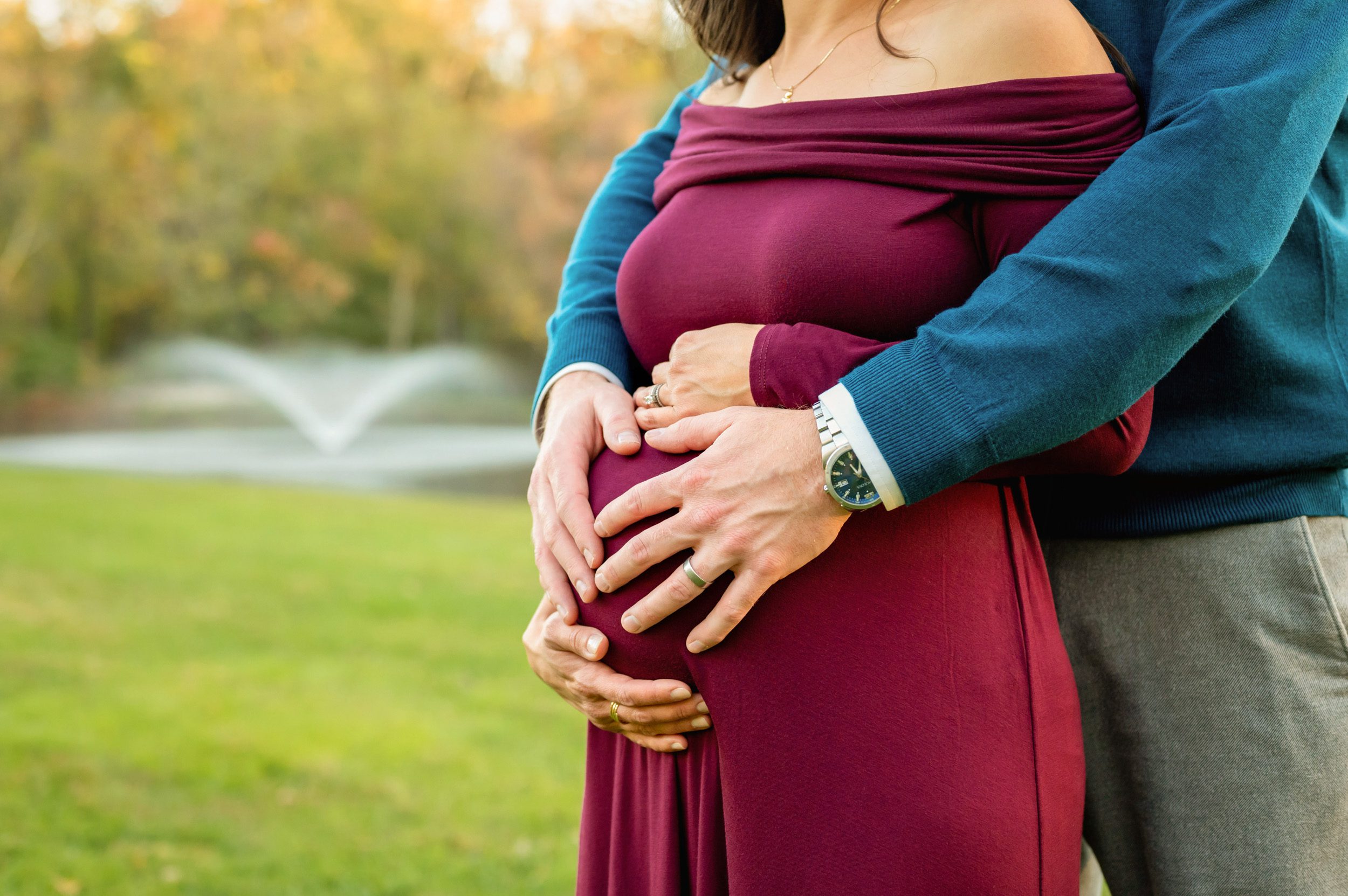 Close up picture of an expecting mother's belly with dad hugging her from behind during a maternity photoshoot