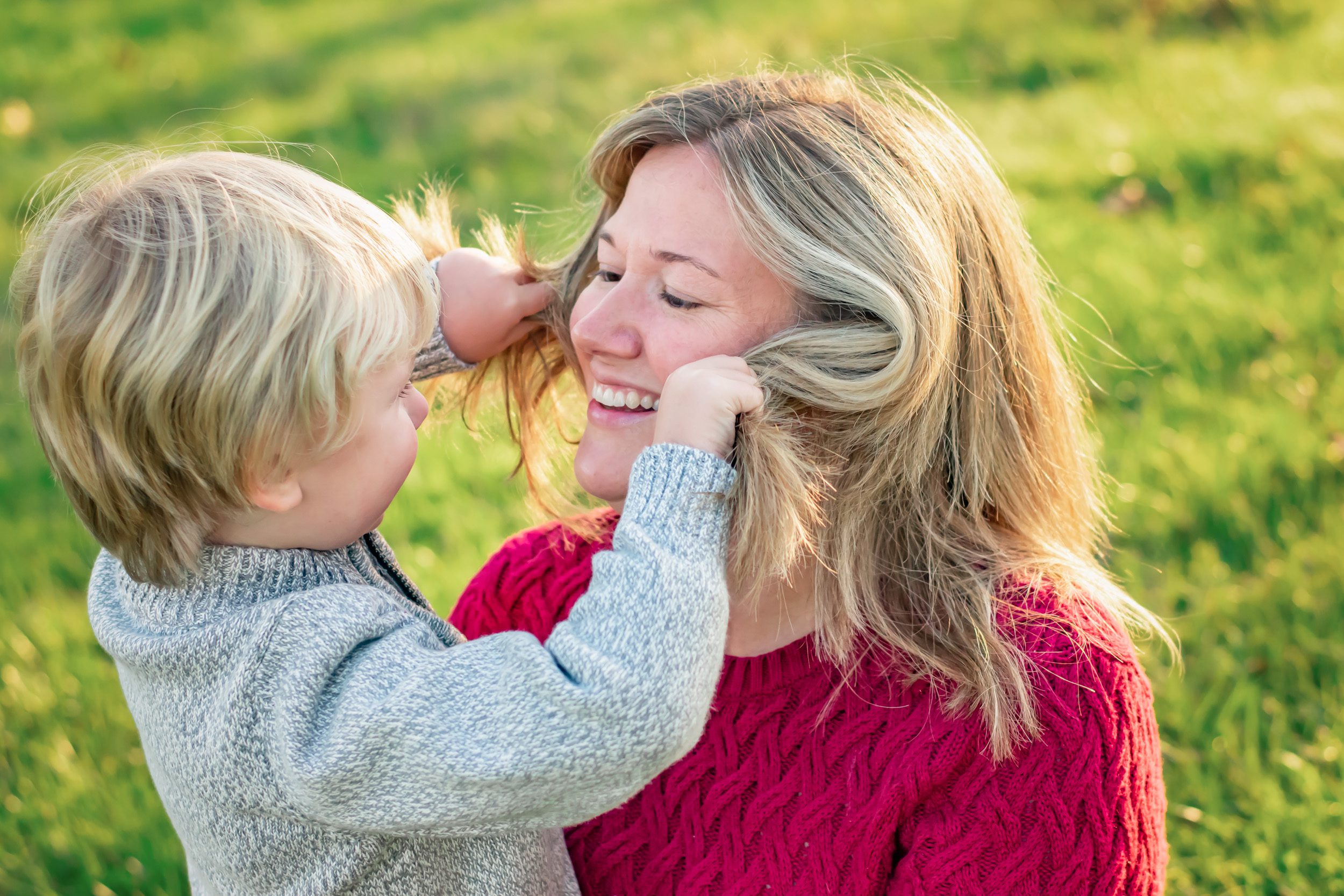 A young boy playing peekaboo with his mother's hair during a family photoshoot