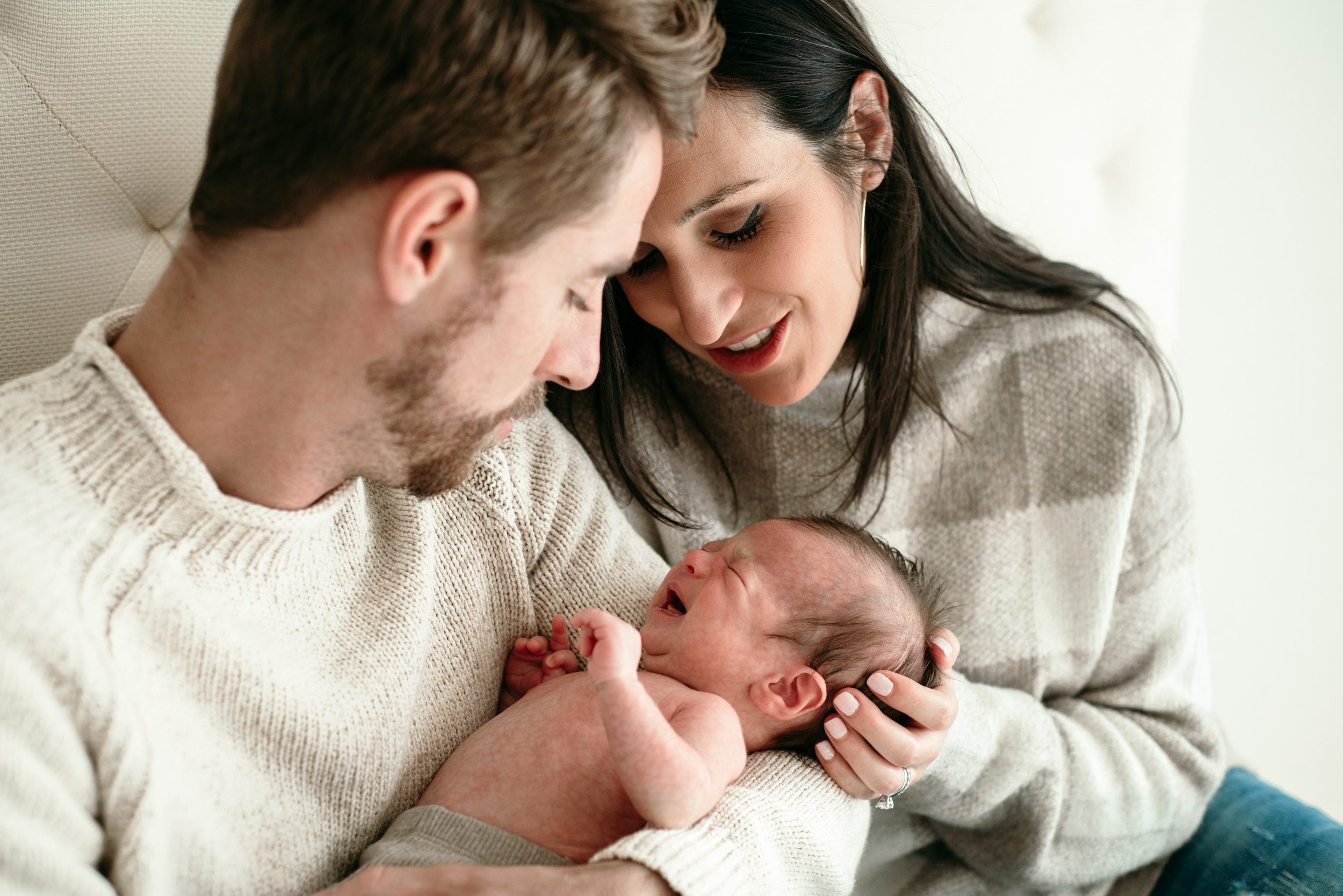 parents comforting their crying newborn son during an in home newborn photography session