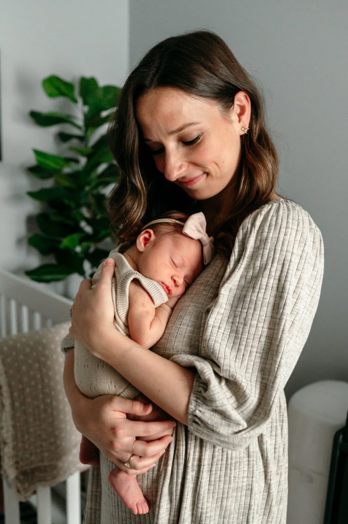 A new mom snuggling her baby girl against her chest during an in home newborn photoshoot