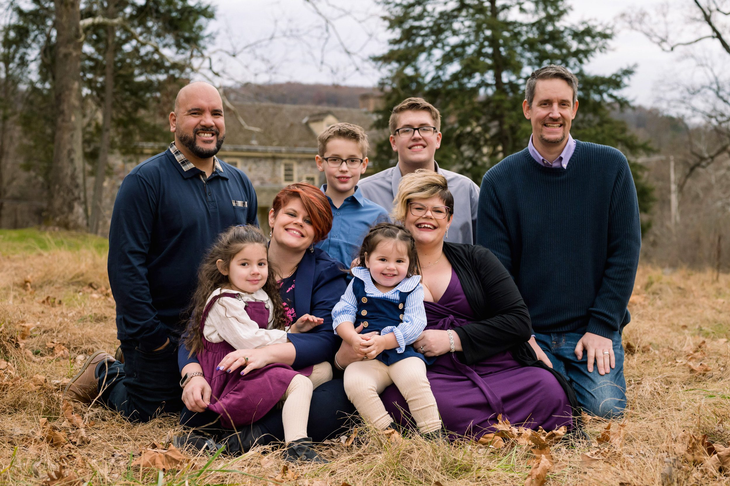 An extended family snuggling together in a grassy field during an extended family photoshoot