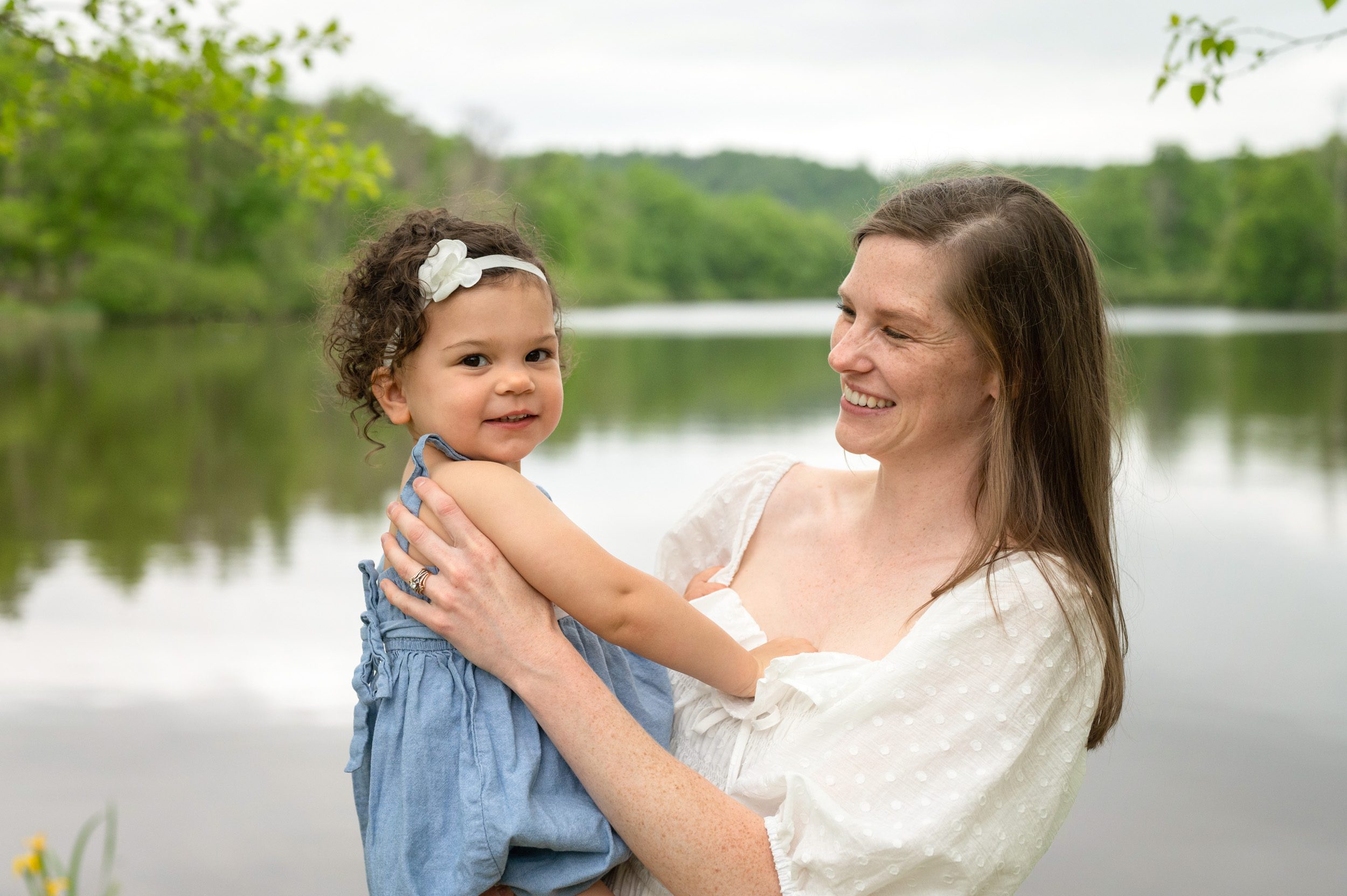 A mom holding her young daughter and smiling at her during a pottstown family photo session