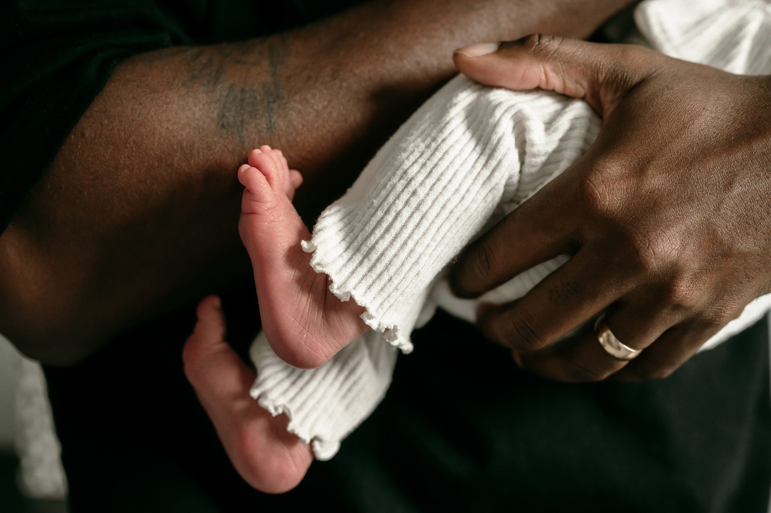 a close up picture of a newborn baby girl's feet as her dad holds her in his arms during a lifestyle newborn photoshoot