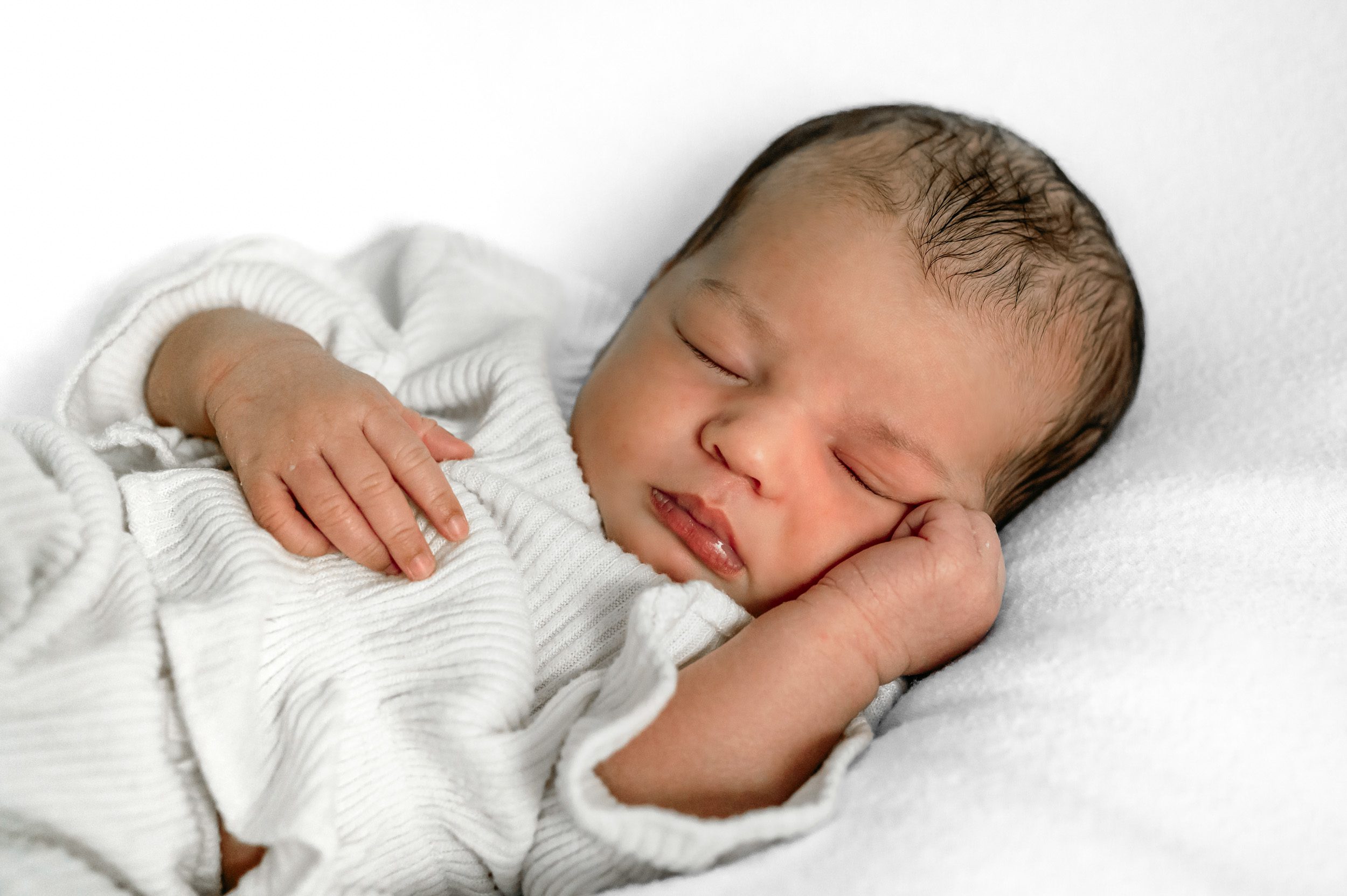 a newborn baby girl laying with her hand under her cheek during a Phoenixville in home newborn photoshoot