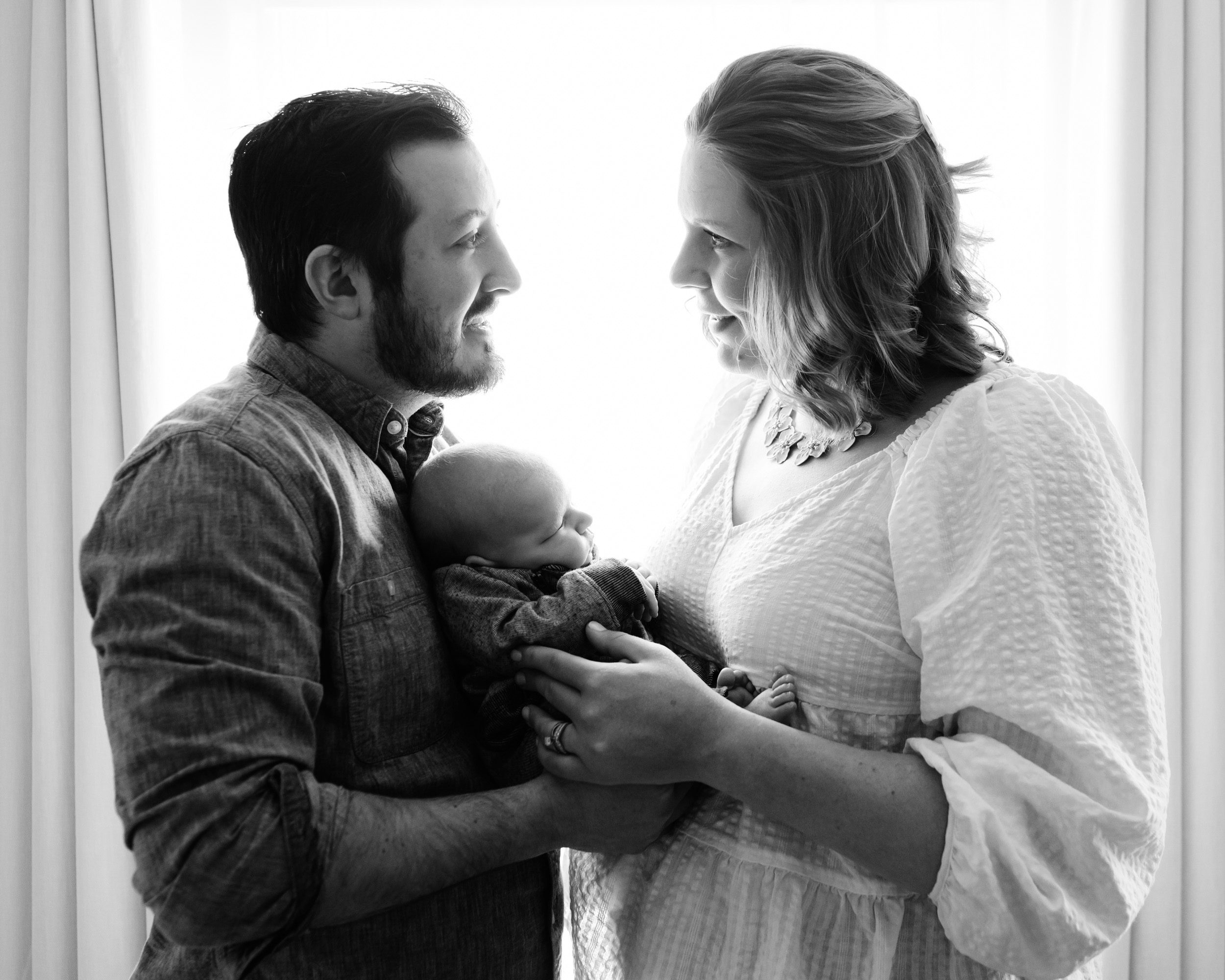 Black and white backlit image of new parents holding their newborn baby boy during a Gilbertsville home newborn session