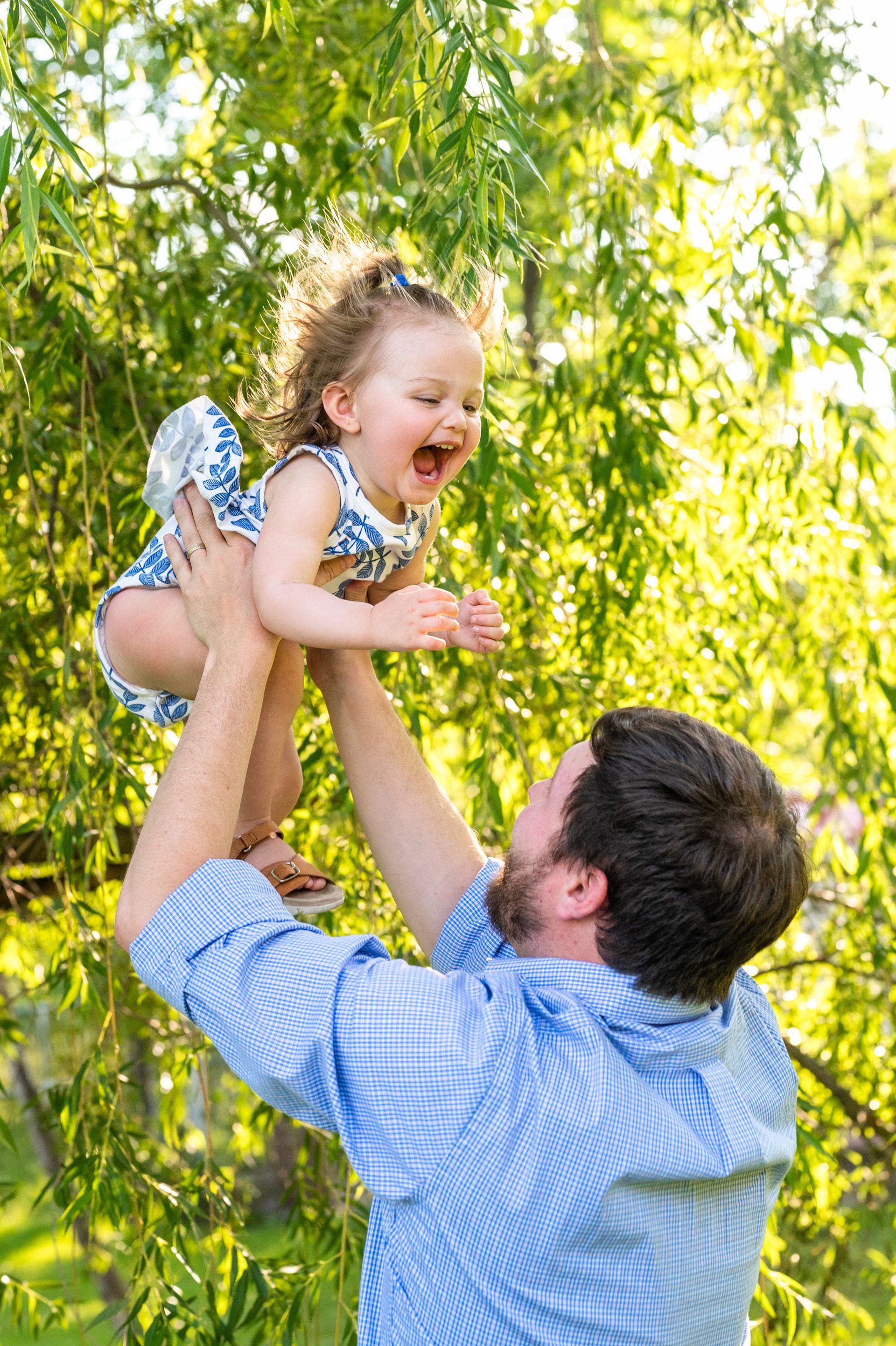 a little girl laughing as her dad flies her up in the air during a Pottstown family photoshoot