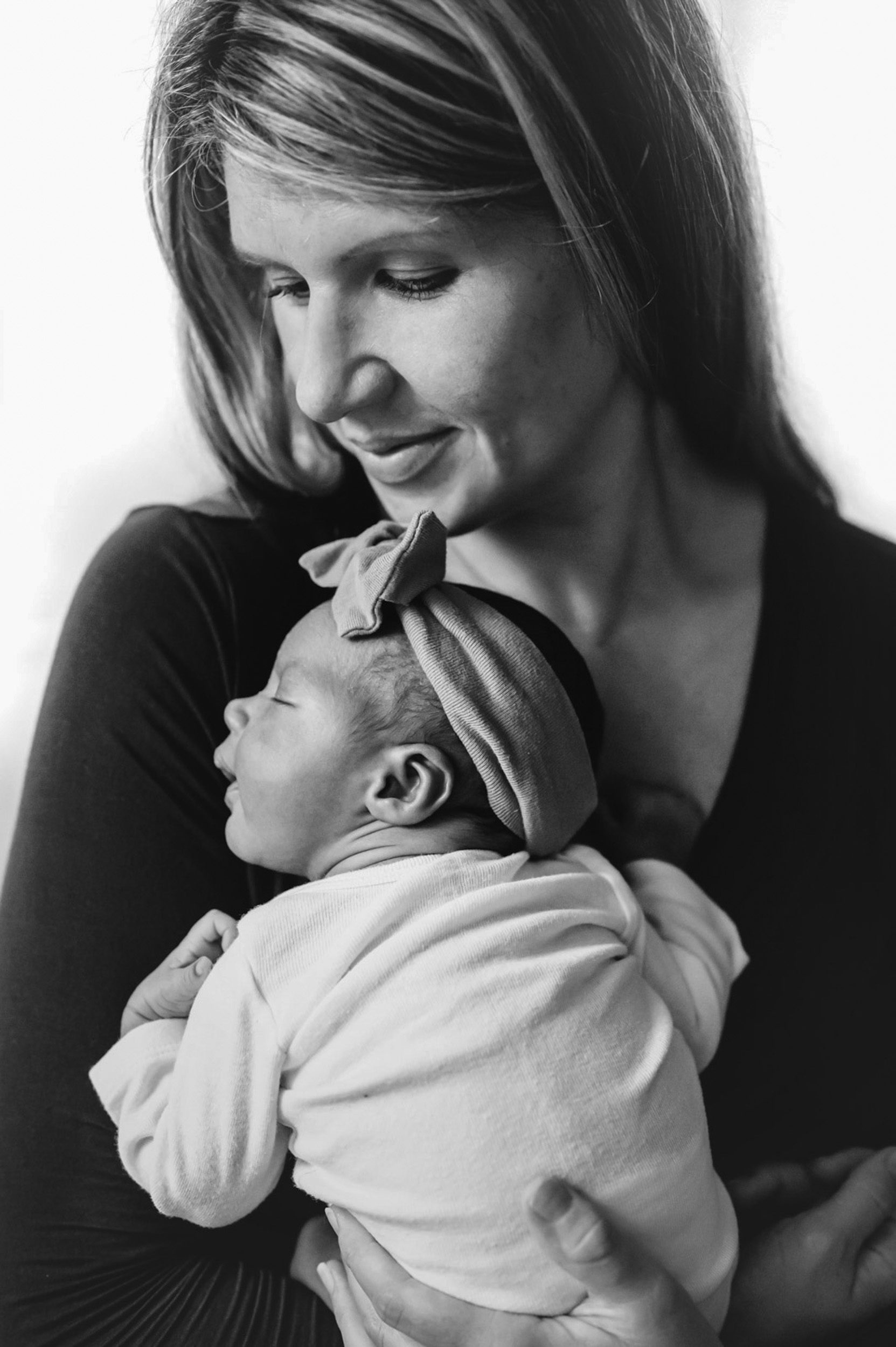 a black and white picture of a mom holding her baby girl against her chest during a lifestyle newborn photo session