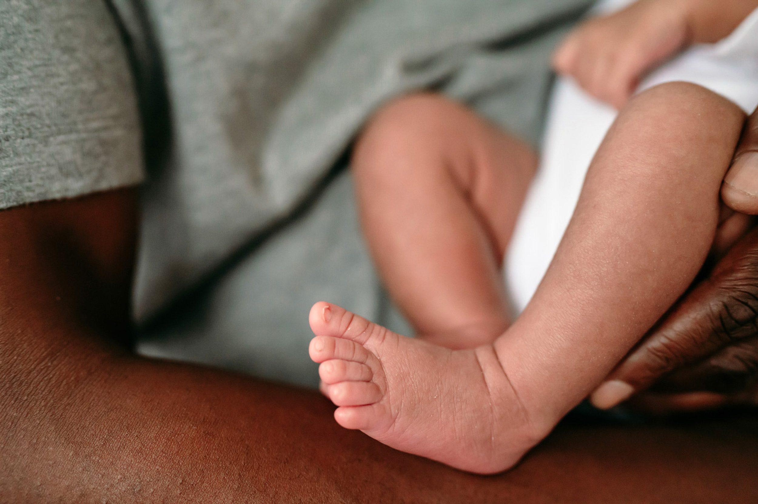 a close up picture of a newborn baby's feet as her dad holds her in his arms during a lifestyle newborn photo session