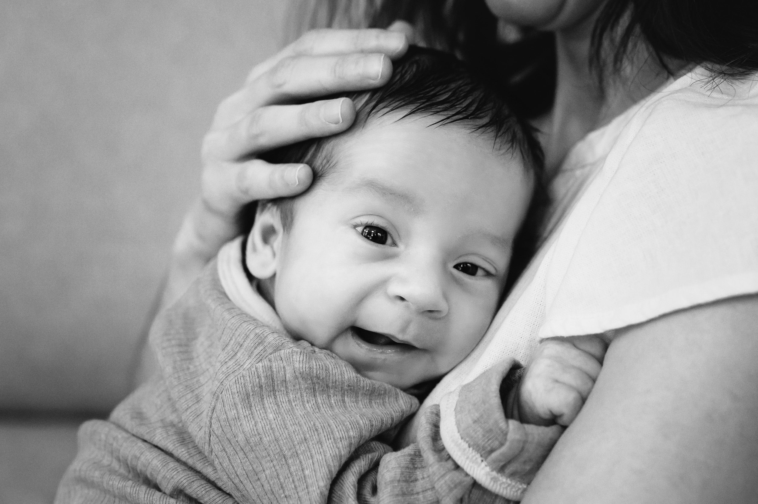 a black and white close up picture of a newborn baby boy looking at the camera during a newborn photoshoot