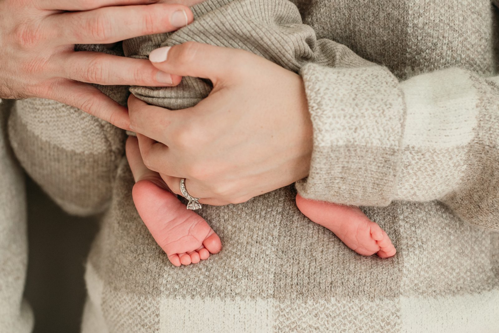 a close up picture of a newborn's feet with his mom and dad's hands holding him during a newborn photoshoot