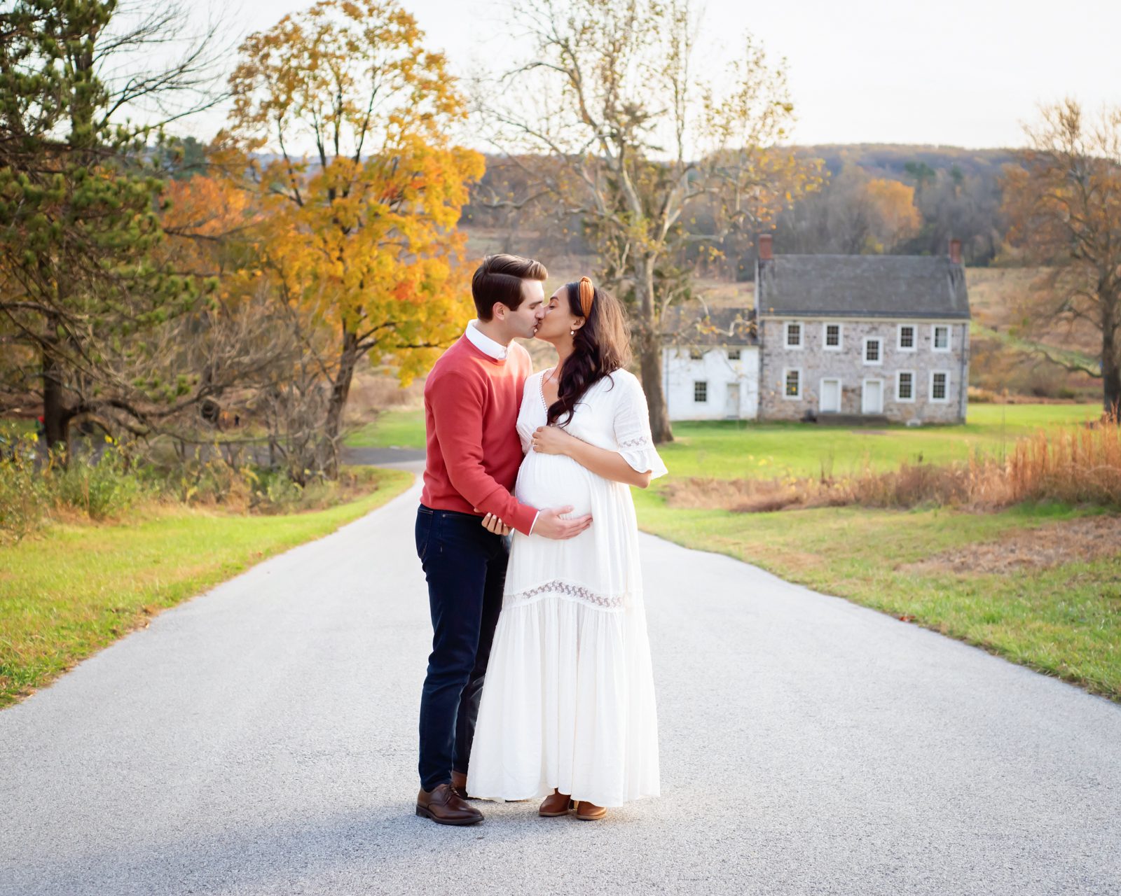 an expecting couple standing on a path and kissing during a valley forge maternity photoshoot