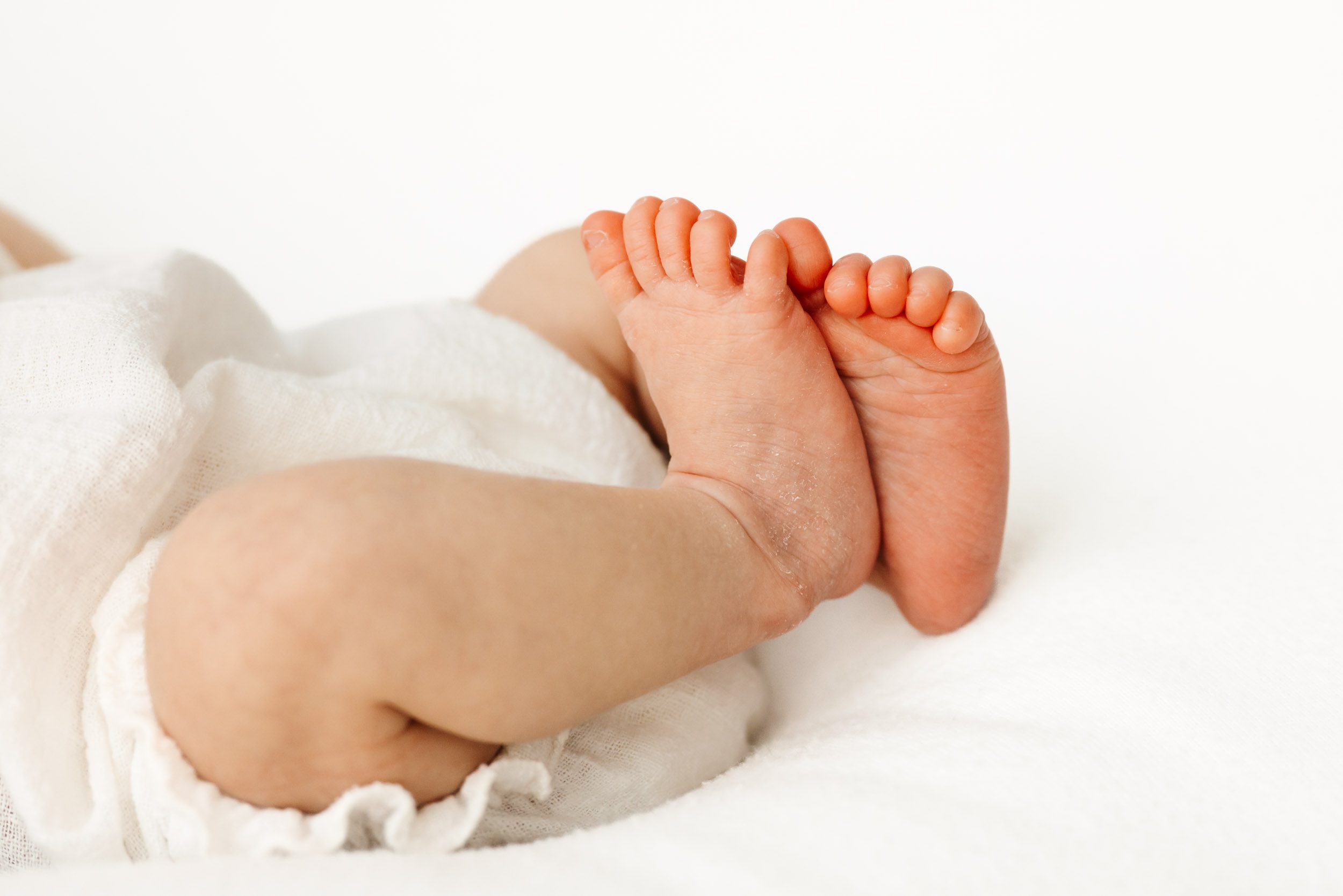 a close up picture of a baby's touching her tiny feet together during a natural newborn photography session