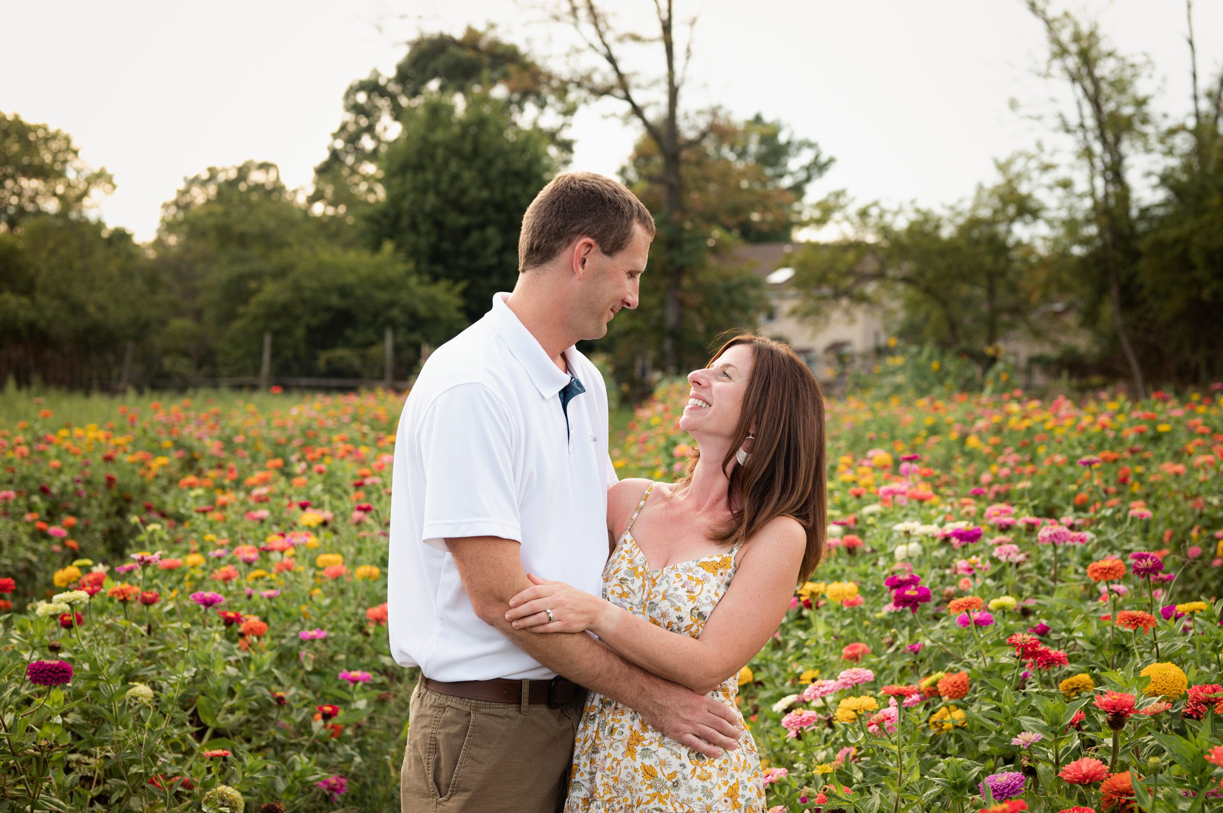 a couple standing in a field of colorful flowers and smiling at each other during a family photo session