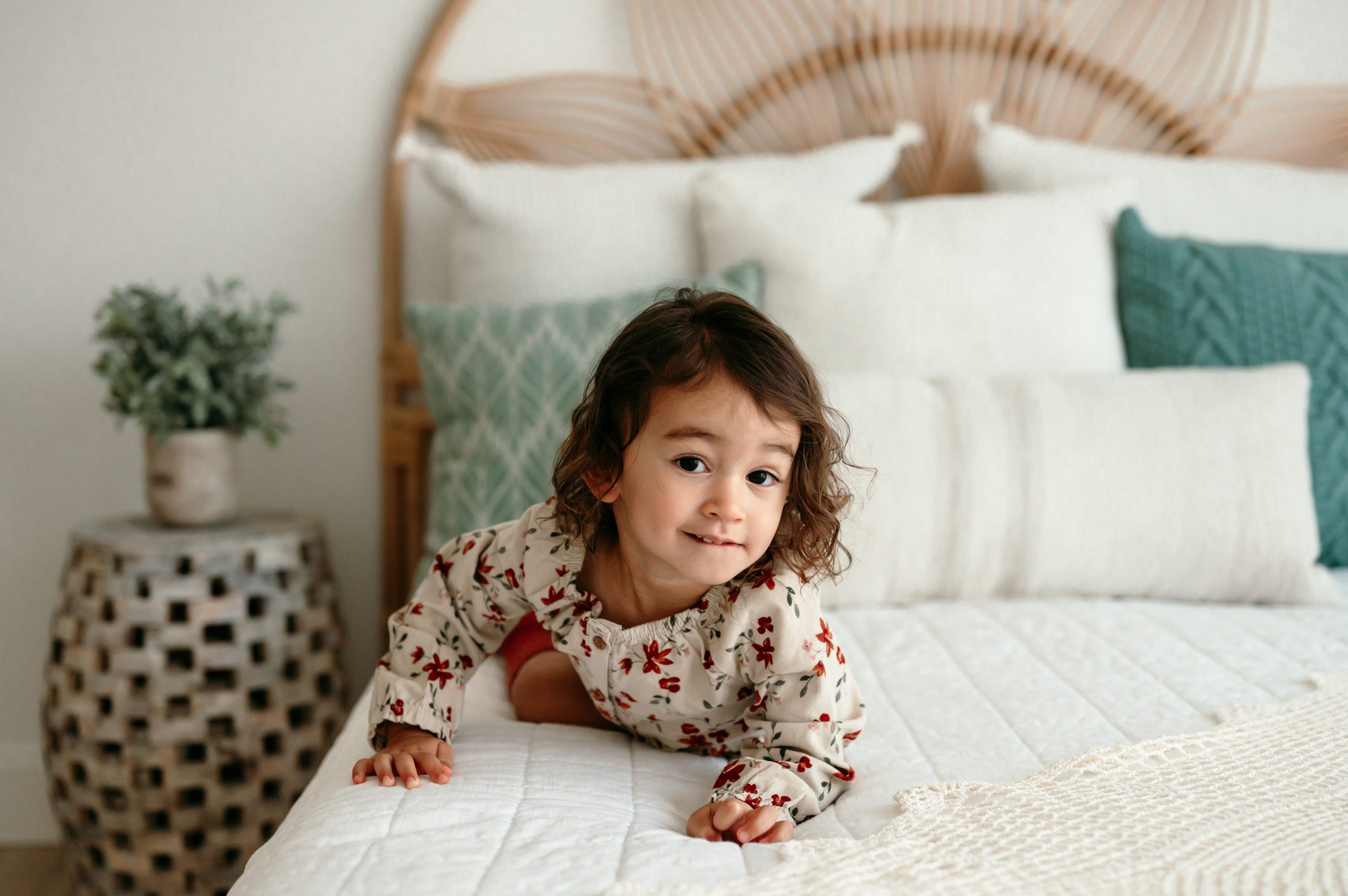 a little girl crawling across a bed like a tiger during a natural light studio photoshoot