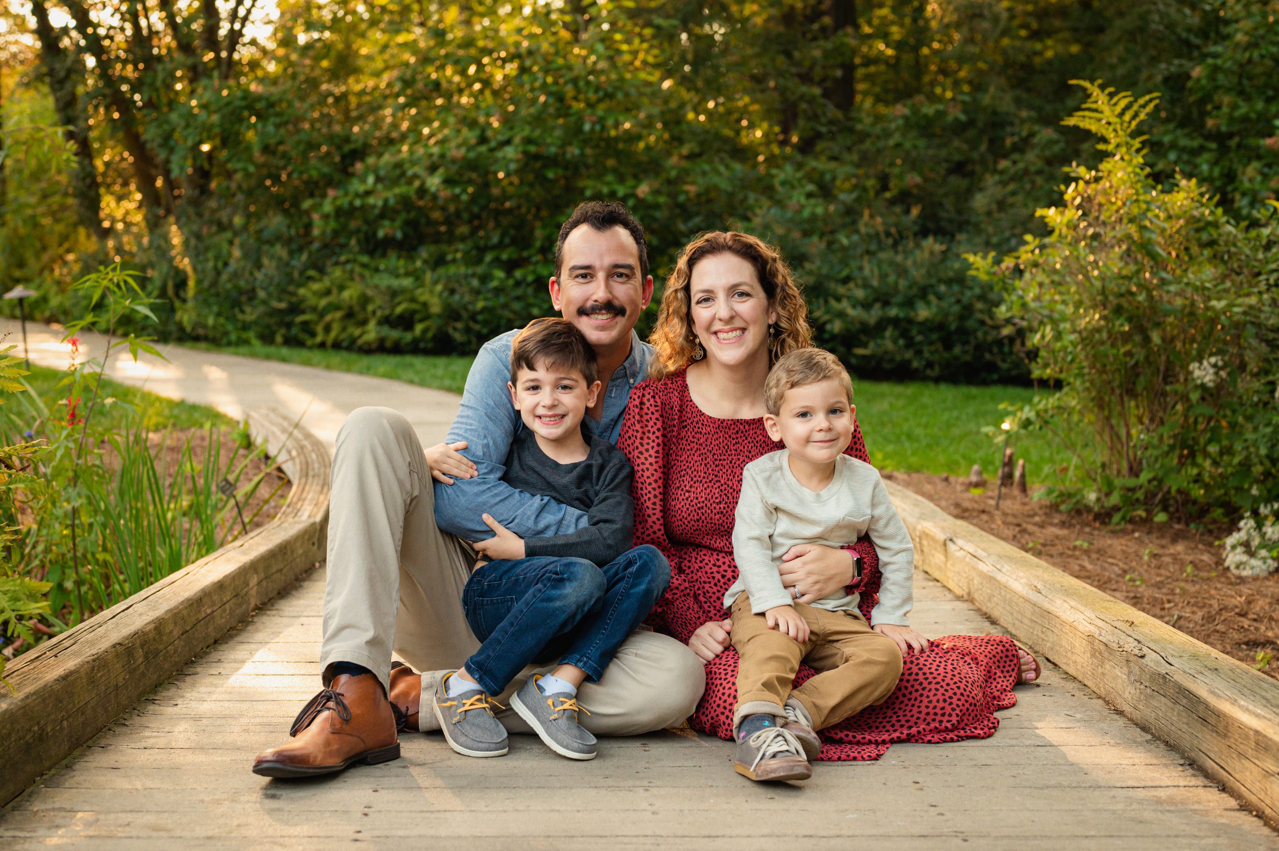 two young boys sitting on their parents lap while everyone smiles at the camera during a West Chester family photoshoot