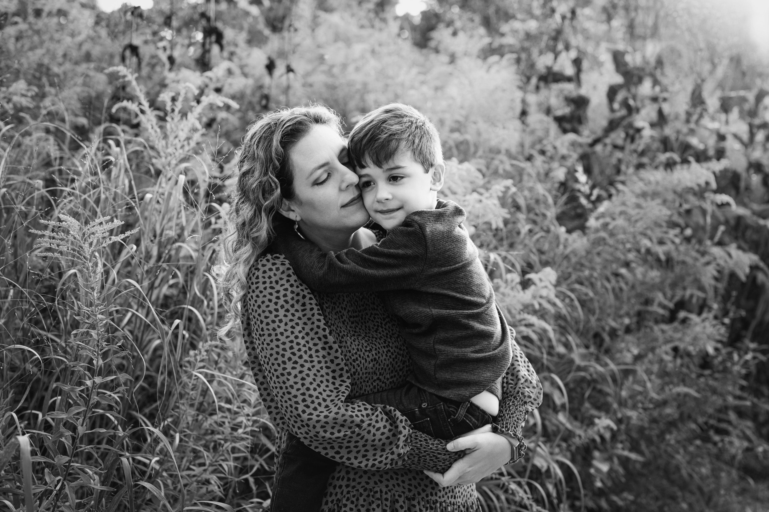 a black and white picture of a mom holding her young son in a field of flowers during a family photoshoot
