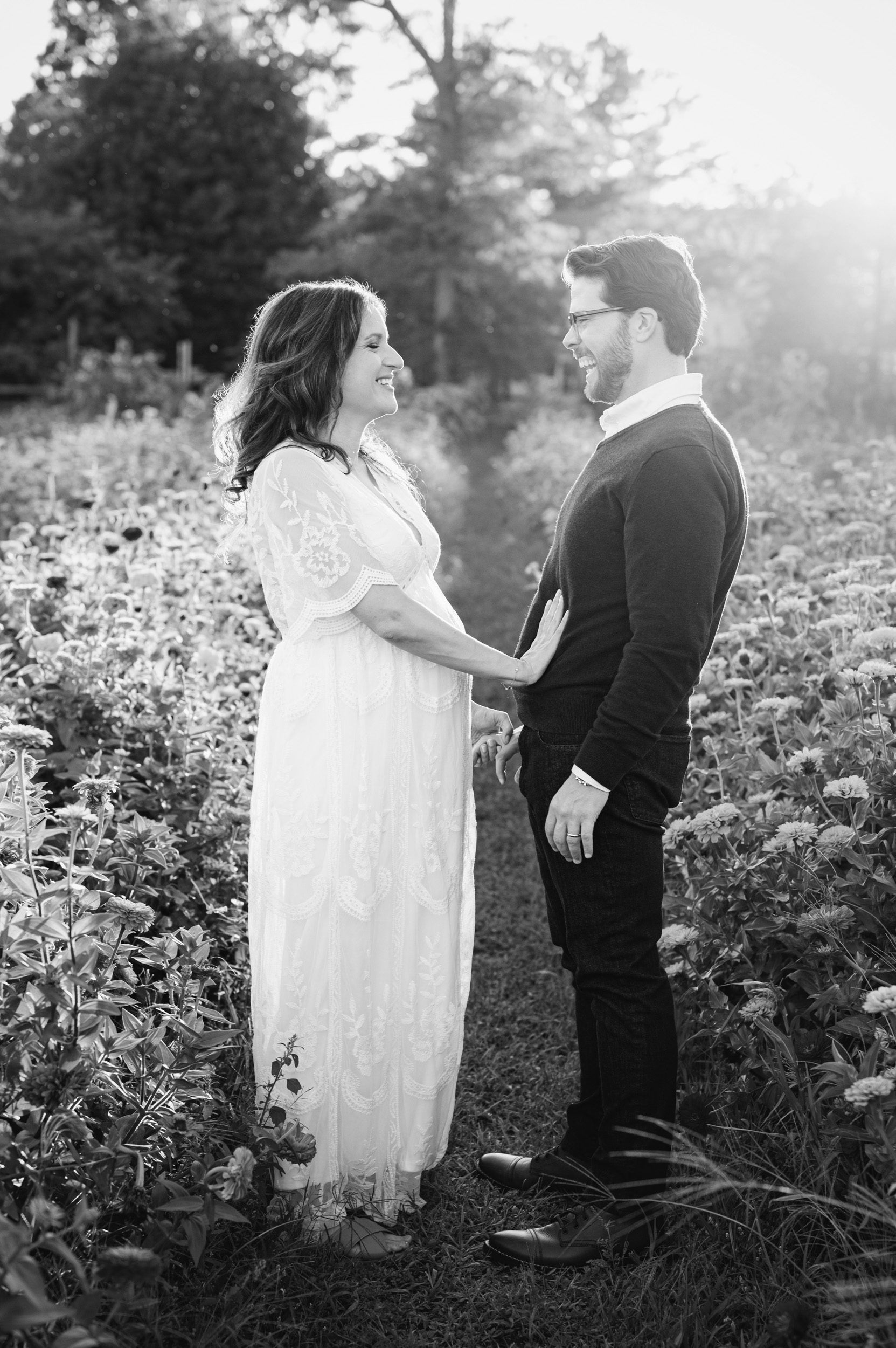 a black and white picture of an expecting couple holding hands and laughing during a Philadelphia maternity photoshoot