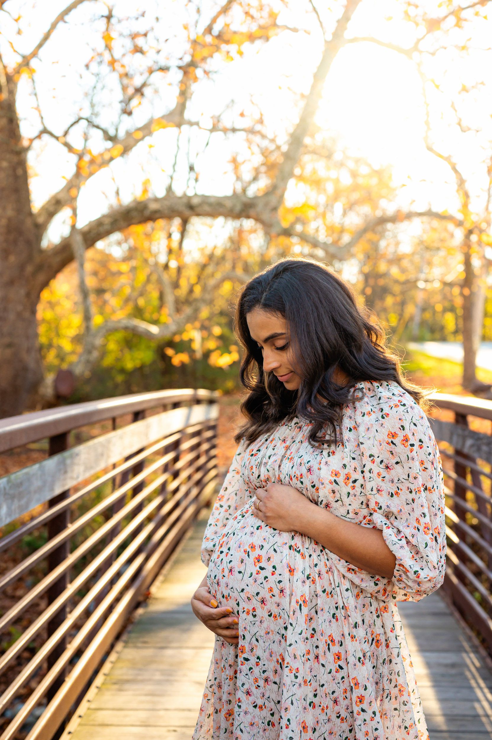 an expecting mother standing on her bridge and smiling down at her belly during a maternity photoshoot