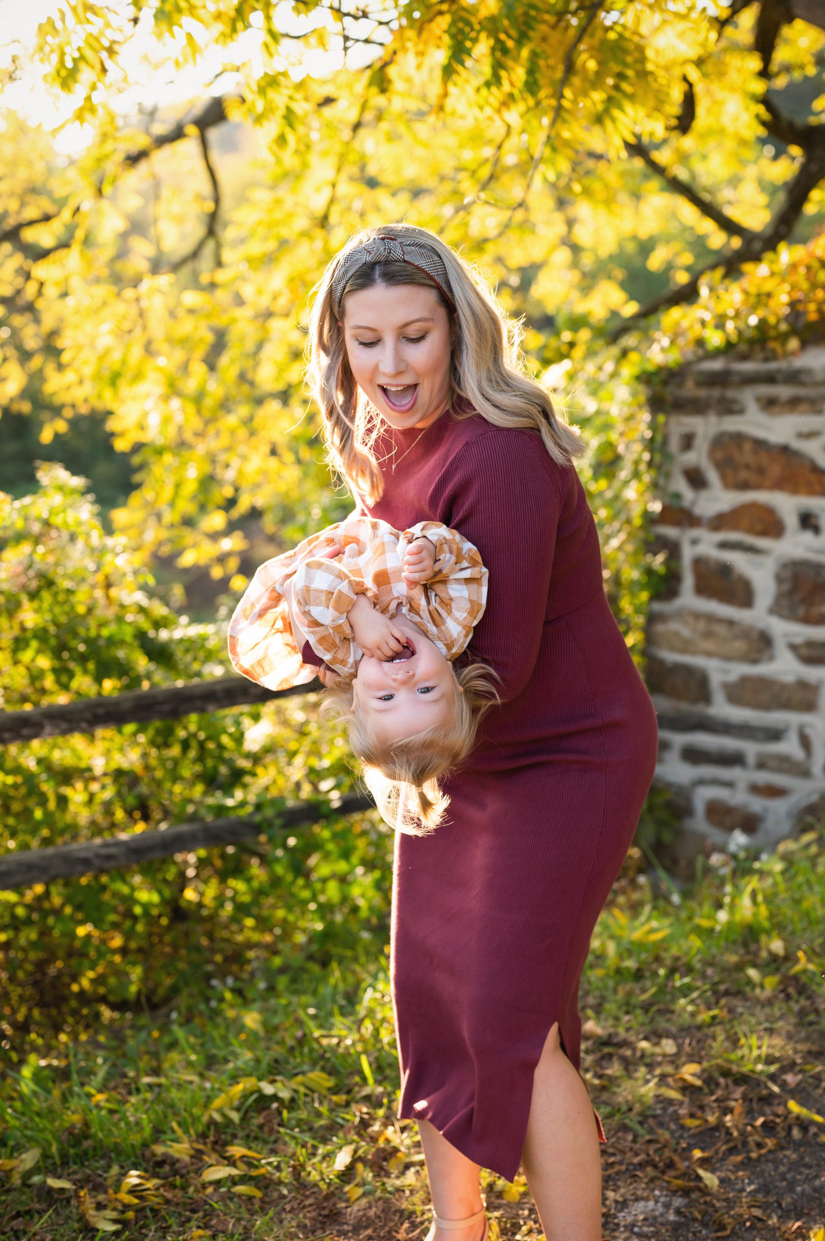 an expecting mom flipping her young daughter upside down during a maternity photo session