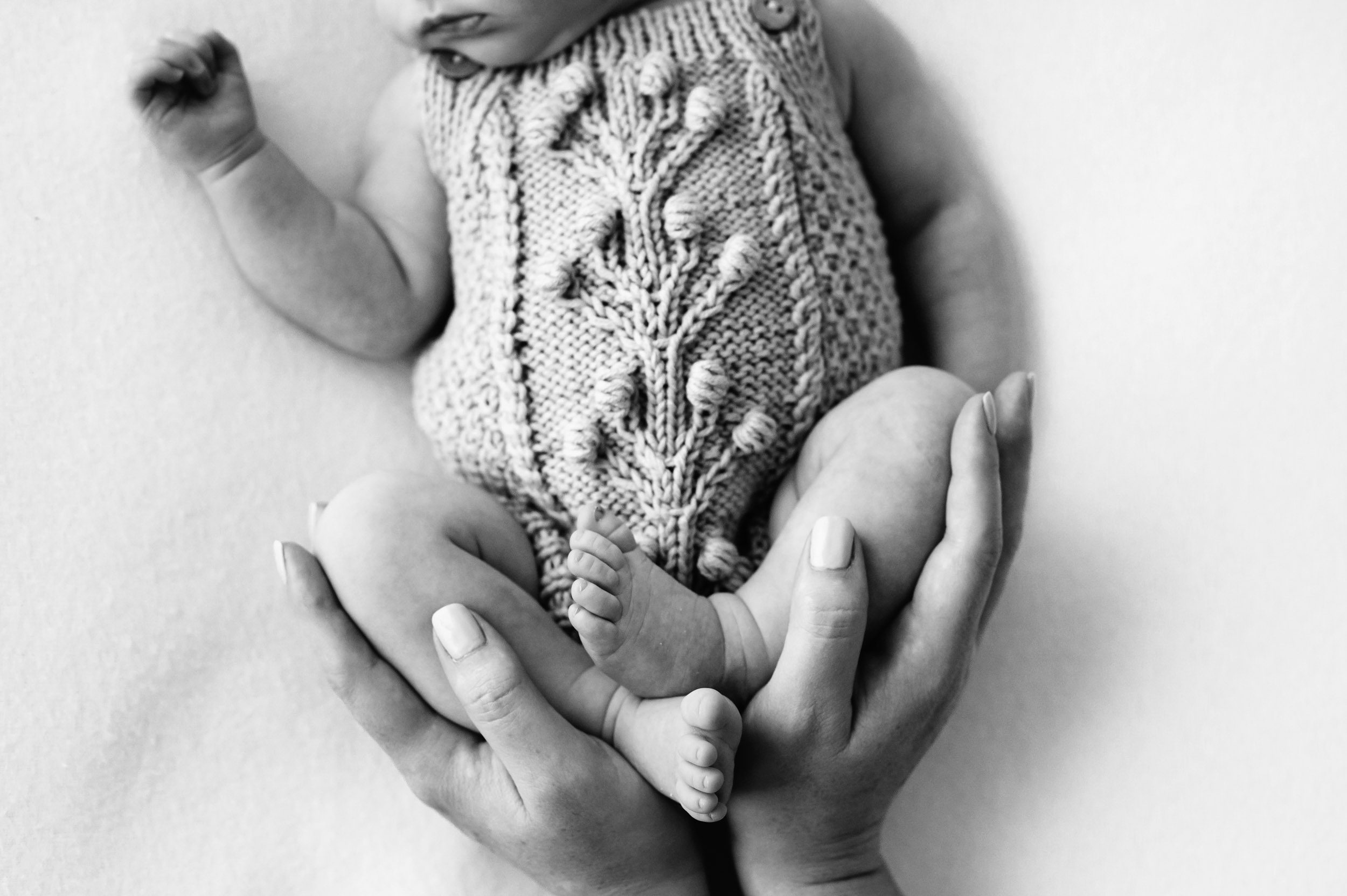 a black and white close up picture of a baby girl's feet cradled in her mom's hands