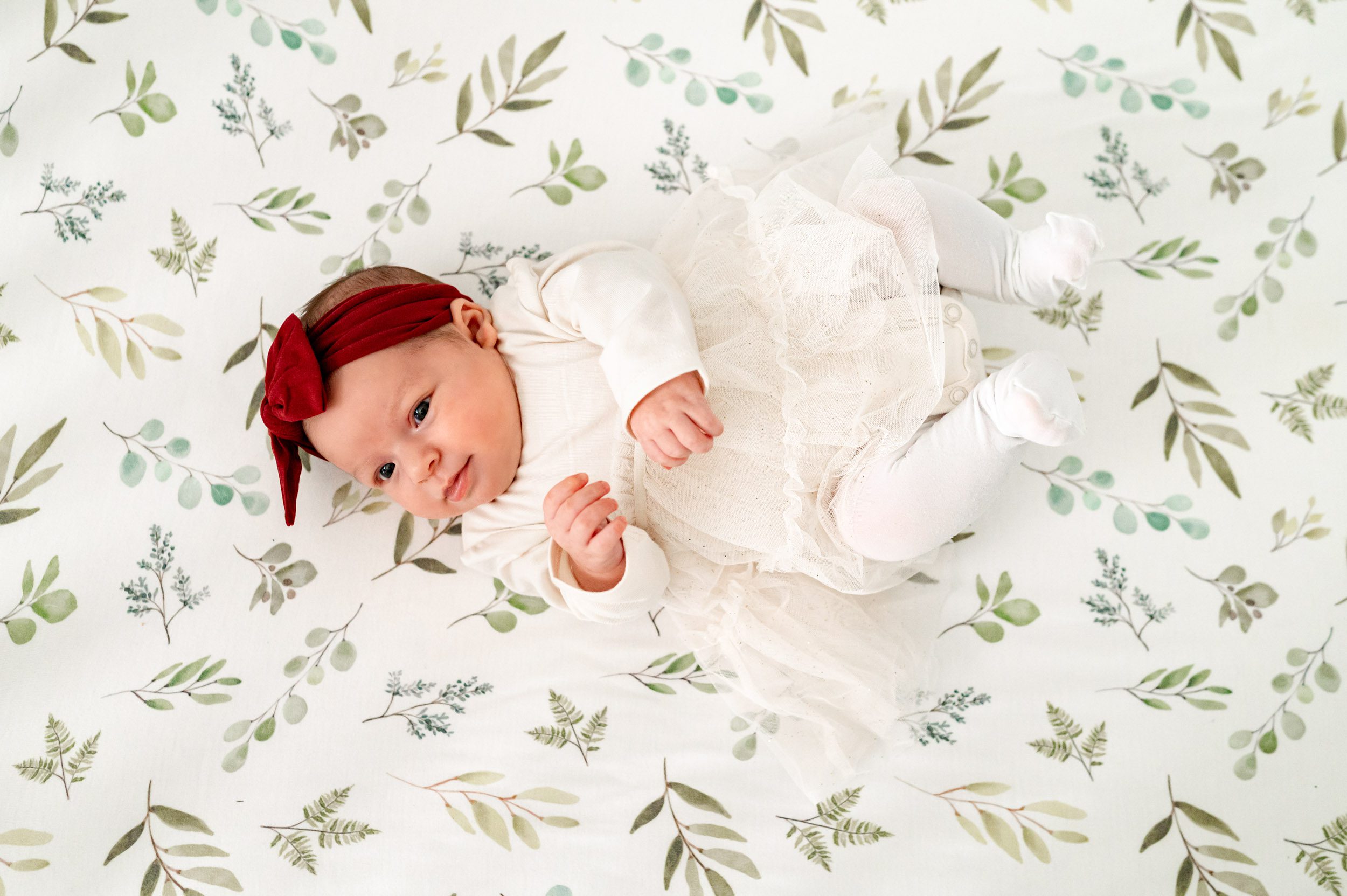 a baby girl laying in her crib and looking up at her mom during a newborn photography session