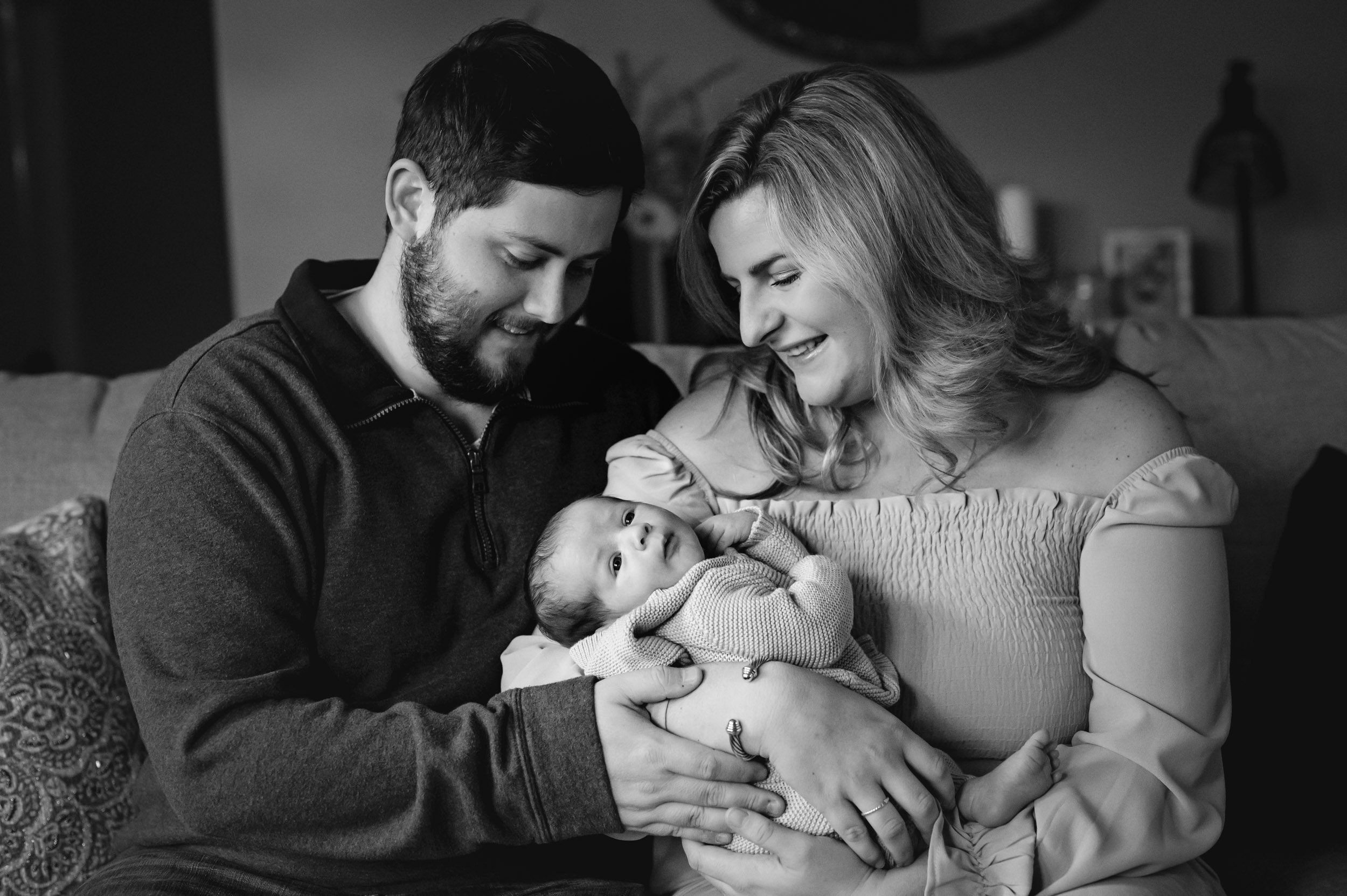 a black and white picture of new parents holding their baby boy in their arms and smiling down at him