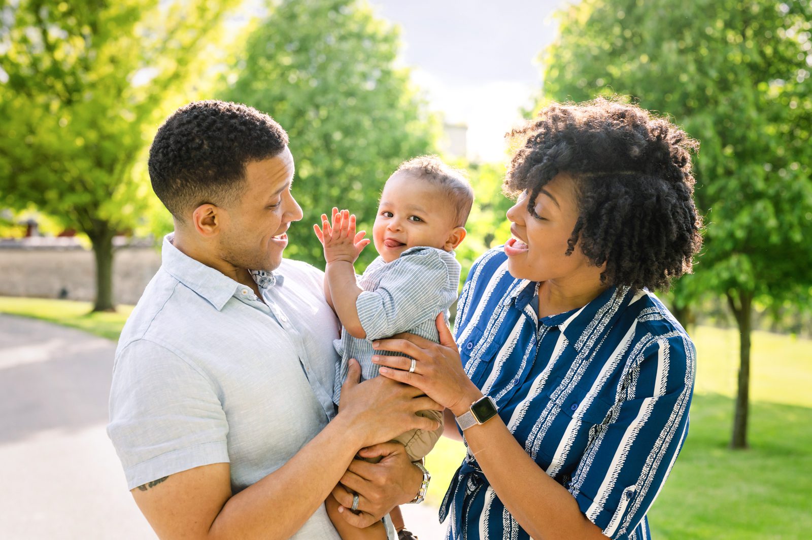 a little boy clapping his hands while his parents hug him from both sides and laugh with him during a spring family photo session