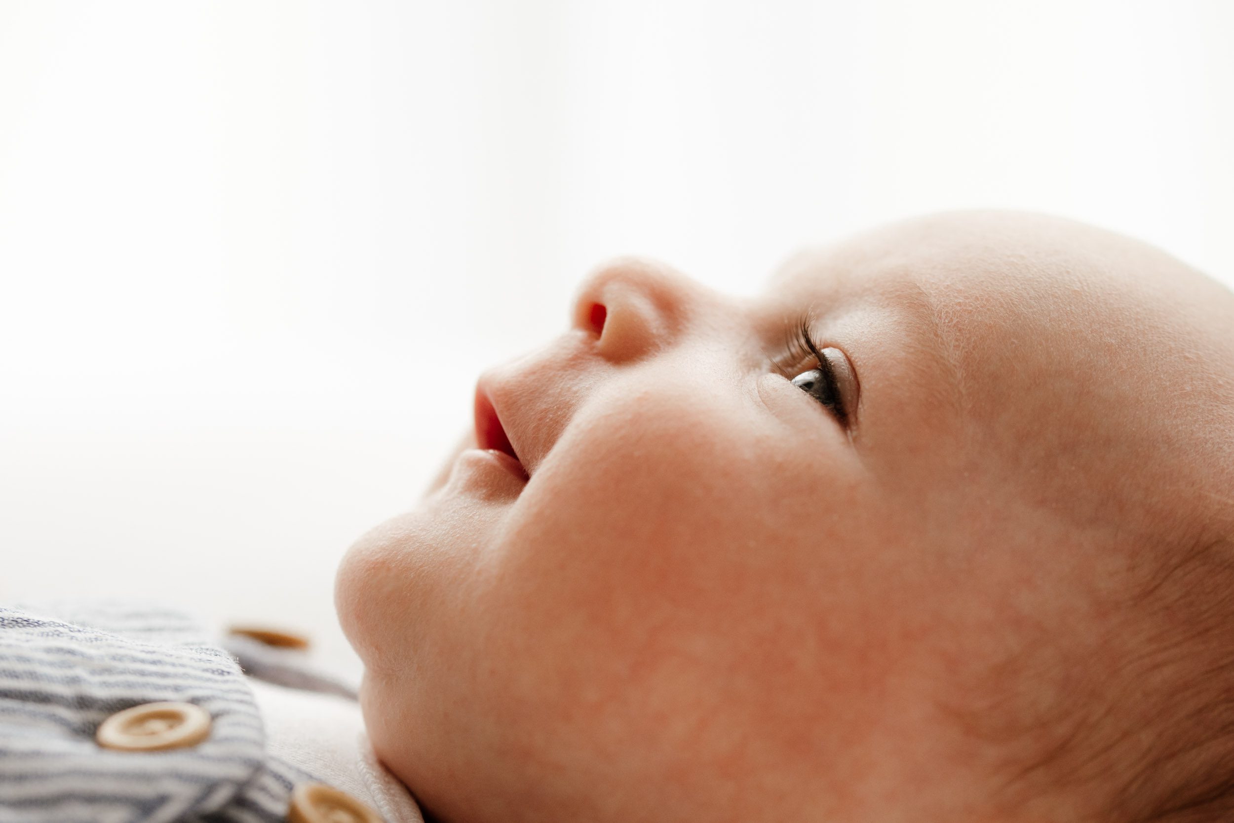 a close up profile picture of a baby boy looking up at his mom with a hint of a smile on his face during a Pottstown newborn photographer session
