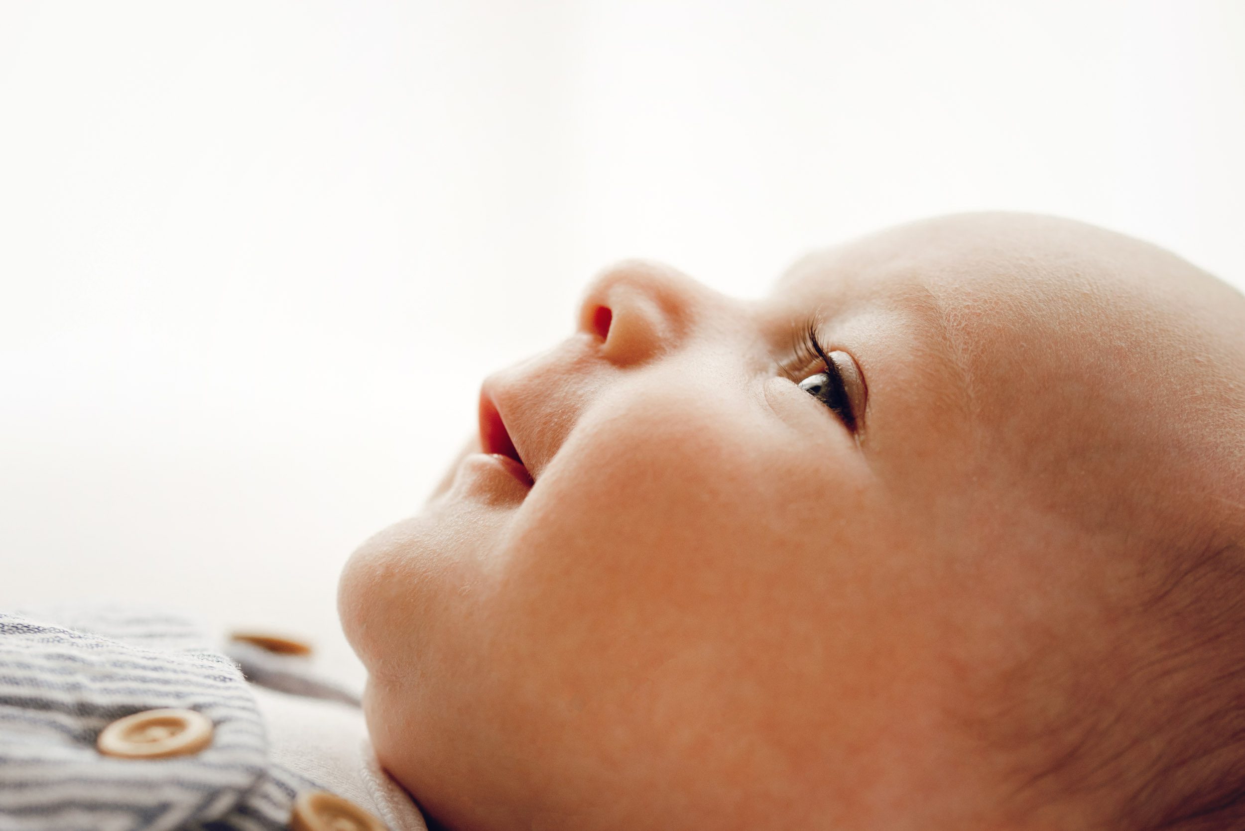 a close up backlit profile picture of a baby boy's face with a focus on his eyelashes taken during a newborn photography session