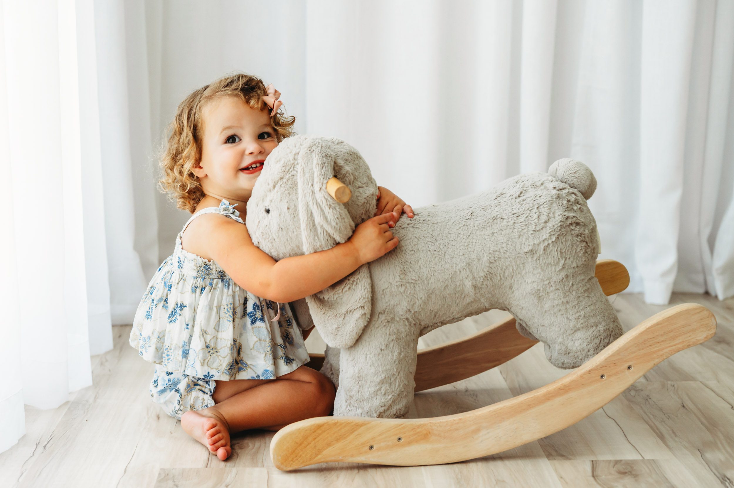 a young girl hugging a bunny rocker toy during a 2nd birthday photoshoot