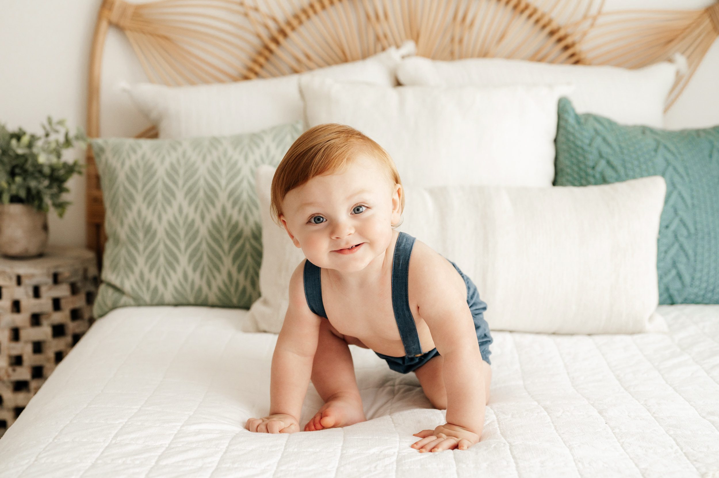 a young boy crawling across a bed as he smiles at the camera 