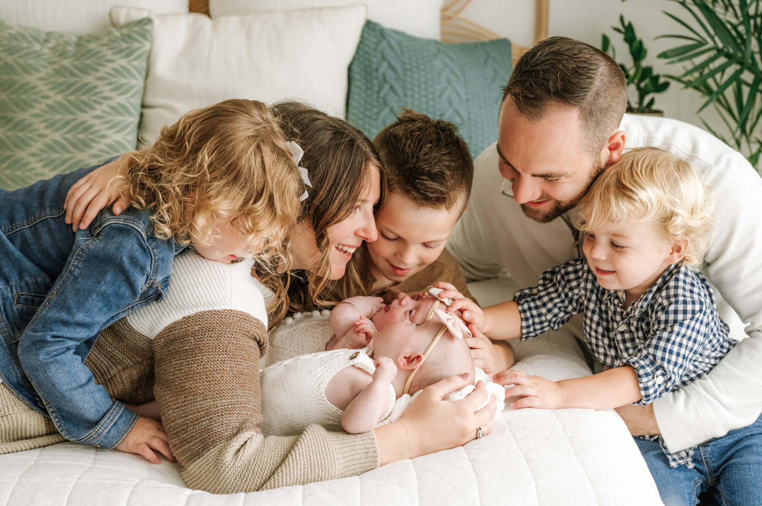 parents laying on a bed with their twin baby girls and three older siblings during a Natural Newborn Photos Session