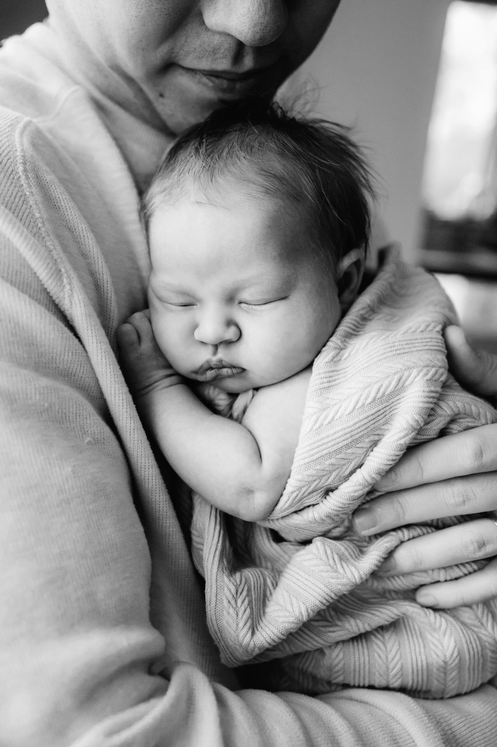 a black and white close up picture of a baby girl sleeping snuggled up against her dad's chest