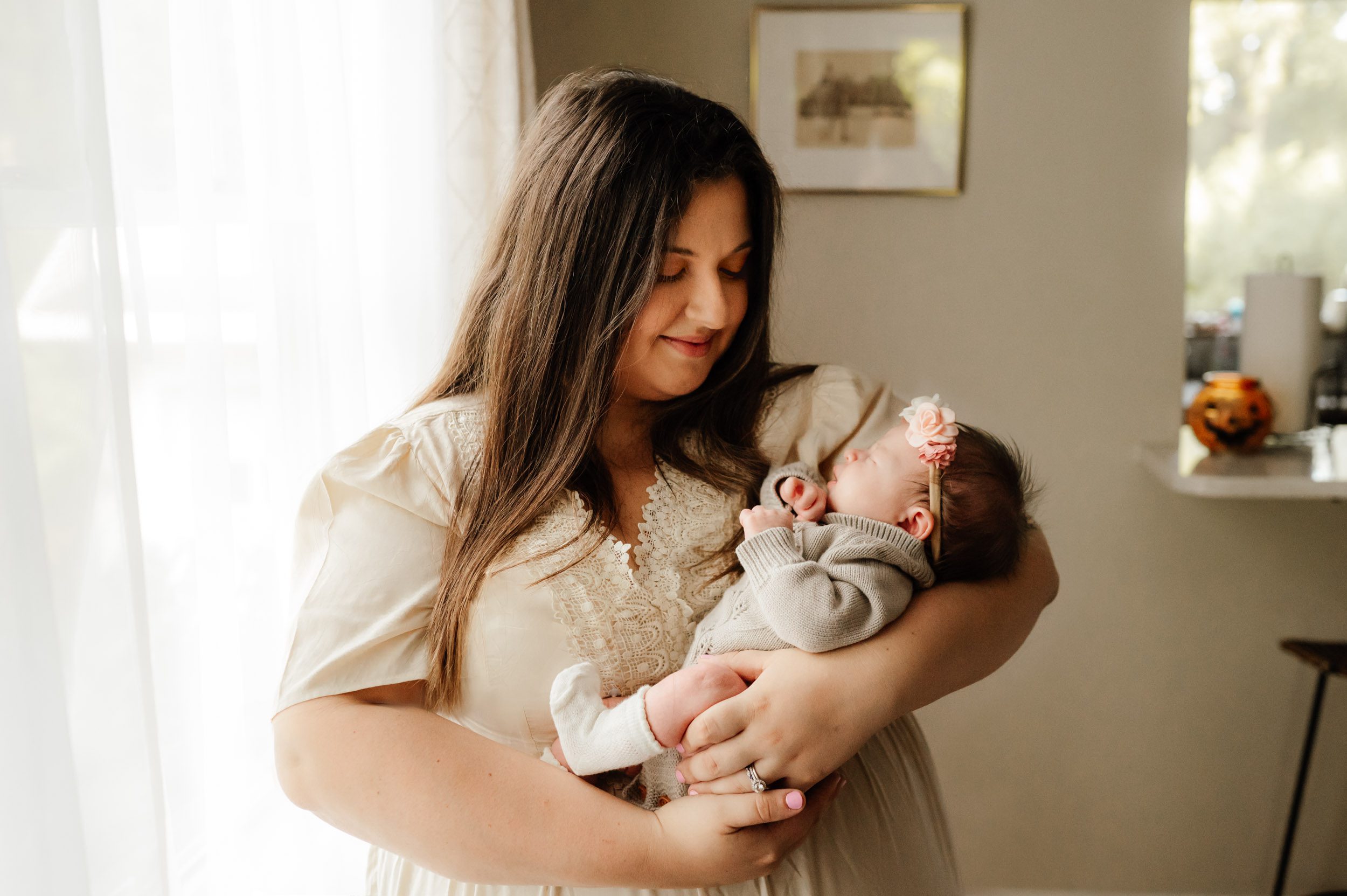 a new mom holding her baby girl cradled in her arms and smiling down at her during a Glenside newborn photography session