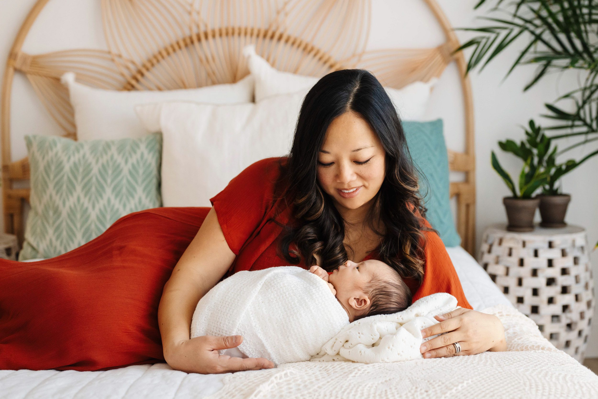 a mom laying on a bed and smiling down at her baby boy during a family centered newborn photos session