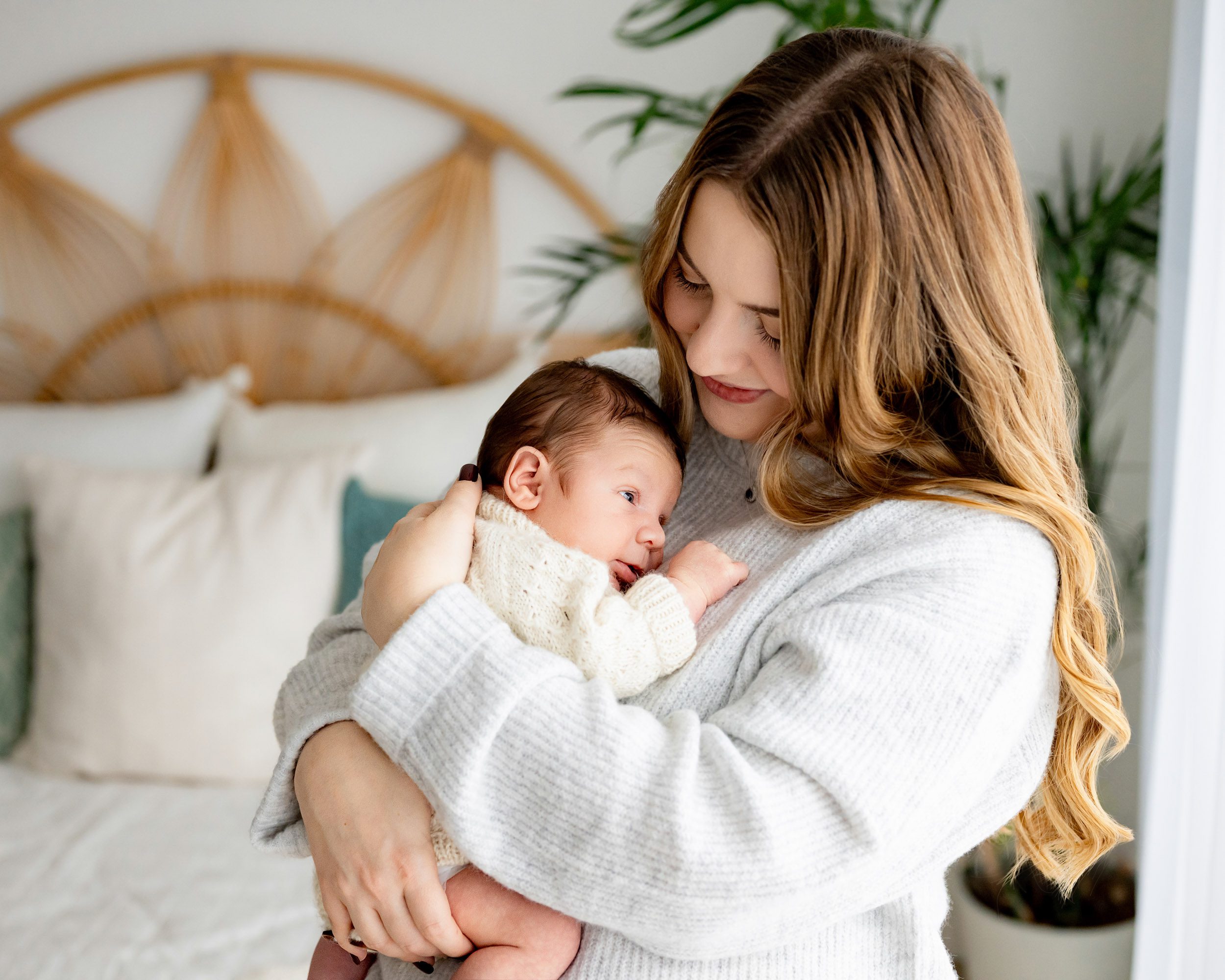 a young boy nestled against his mother's chest as she looks affectionately down at him during a newborn lifestyle photoshoot