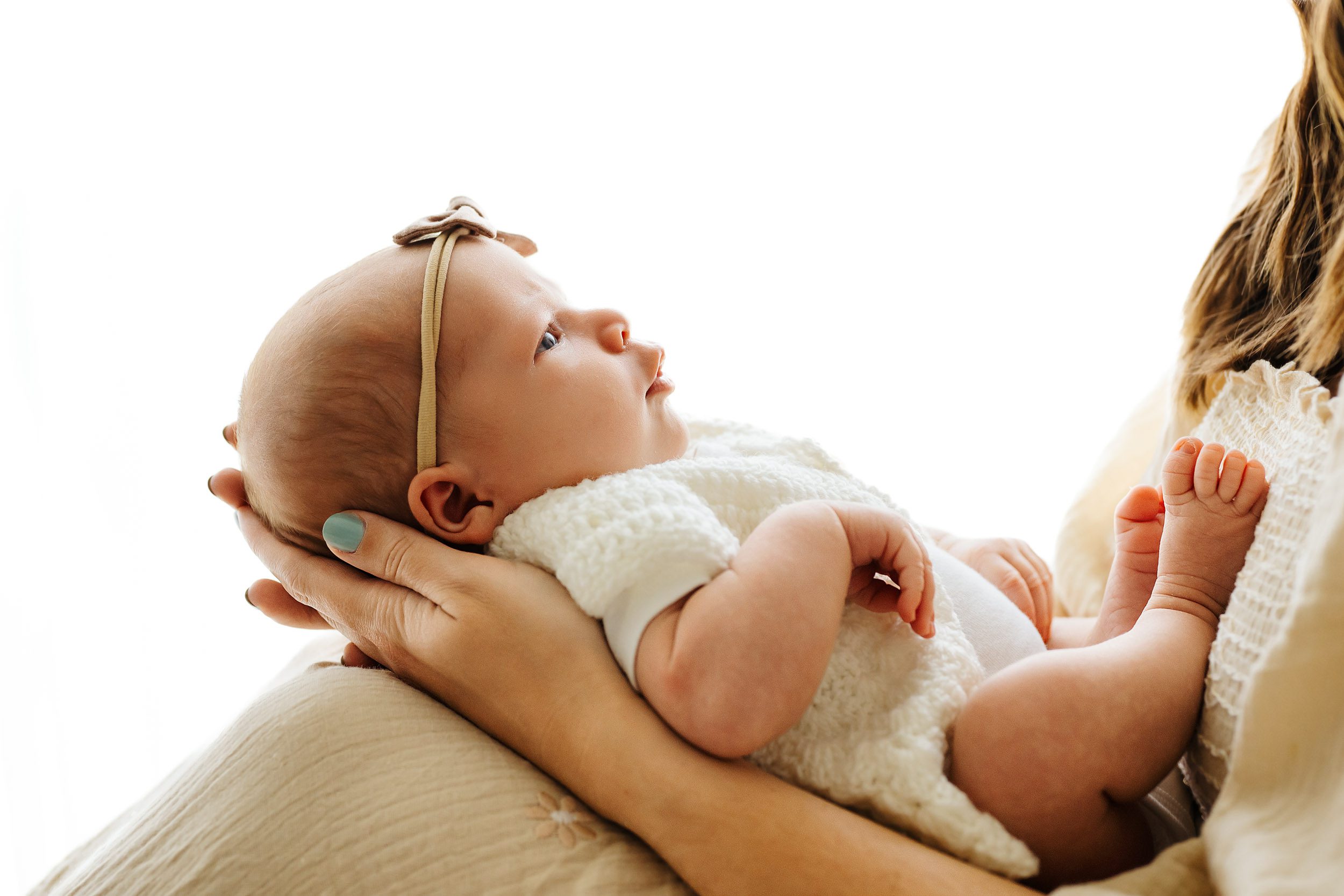 a close up profile photo of a baby girl nestled in her mom's arms during a newborn family photoshoot