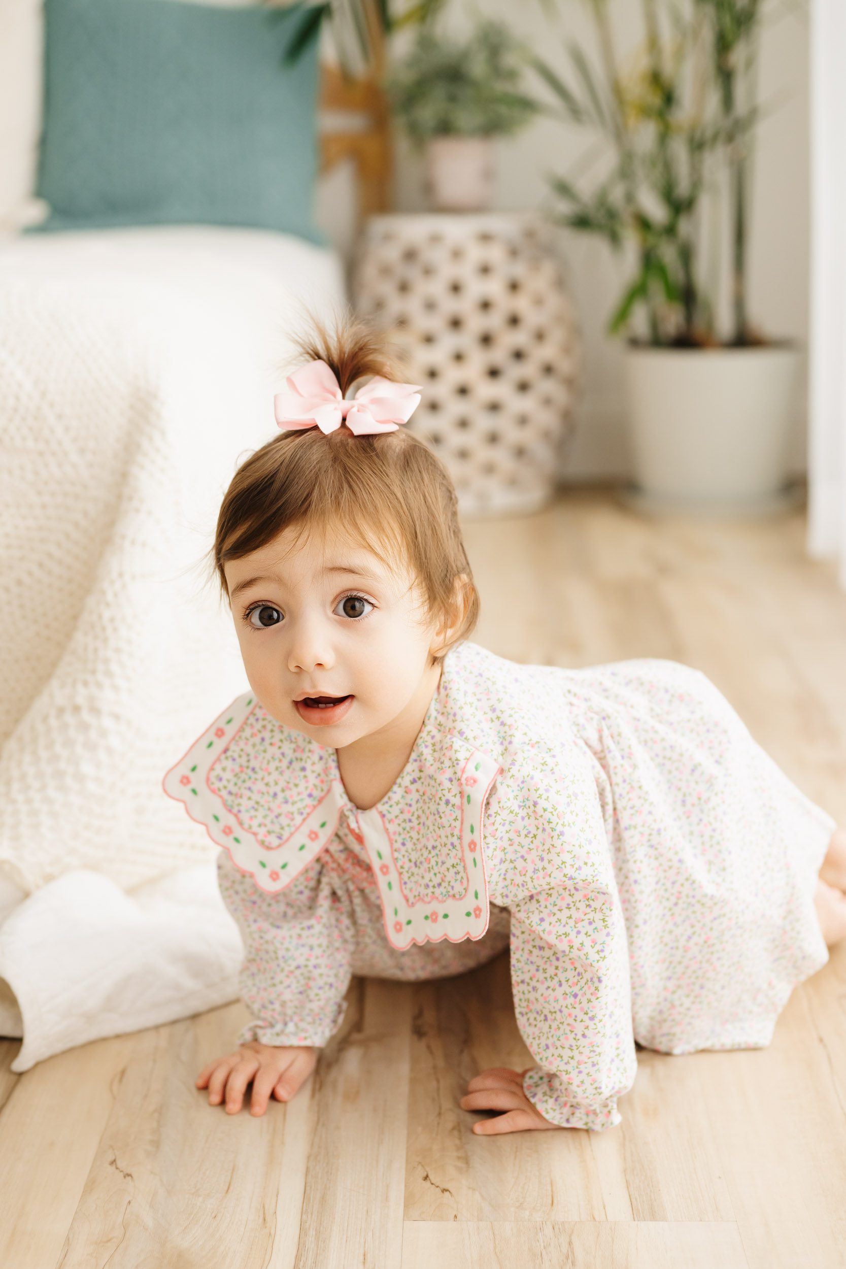 a young girl crawling across the floor and looking directly at the camera during a Pottstown 1st birthday photoshoot