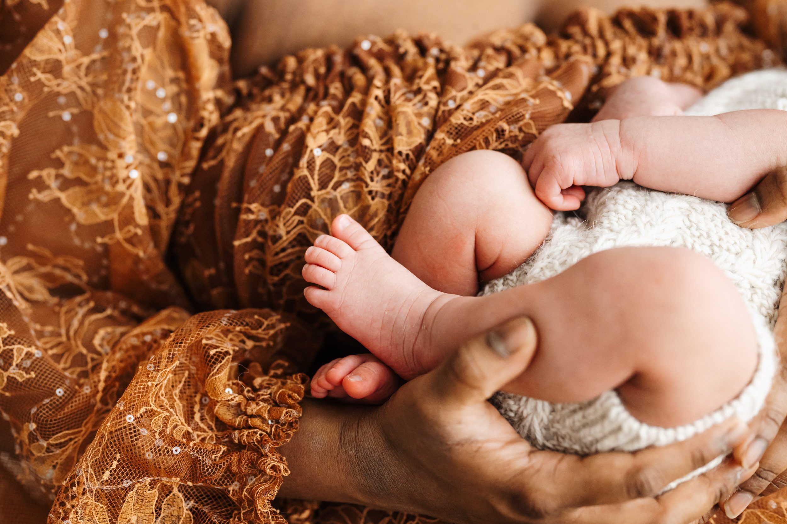 a close up picture of a baby's feet as he snuggles up close to his mom's chest during a newborn photoshoot with mom